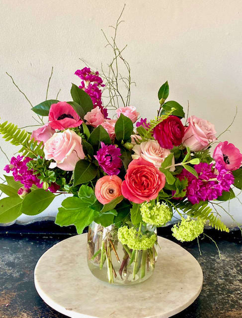 Mixed pink and red flowers arranged in a clear glass vase