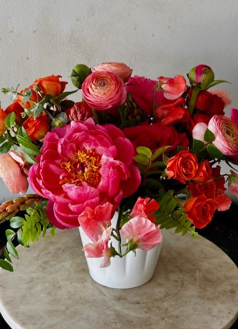 Mother’s Day Collection - Coral Charm - Stunning assortment of premium blooms in coral and deep pink shades: peonies, ranunculus, roses. All arranged in a cheerful ivory cachepot. 