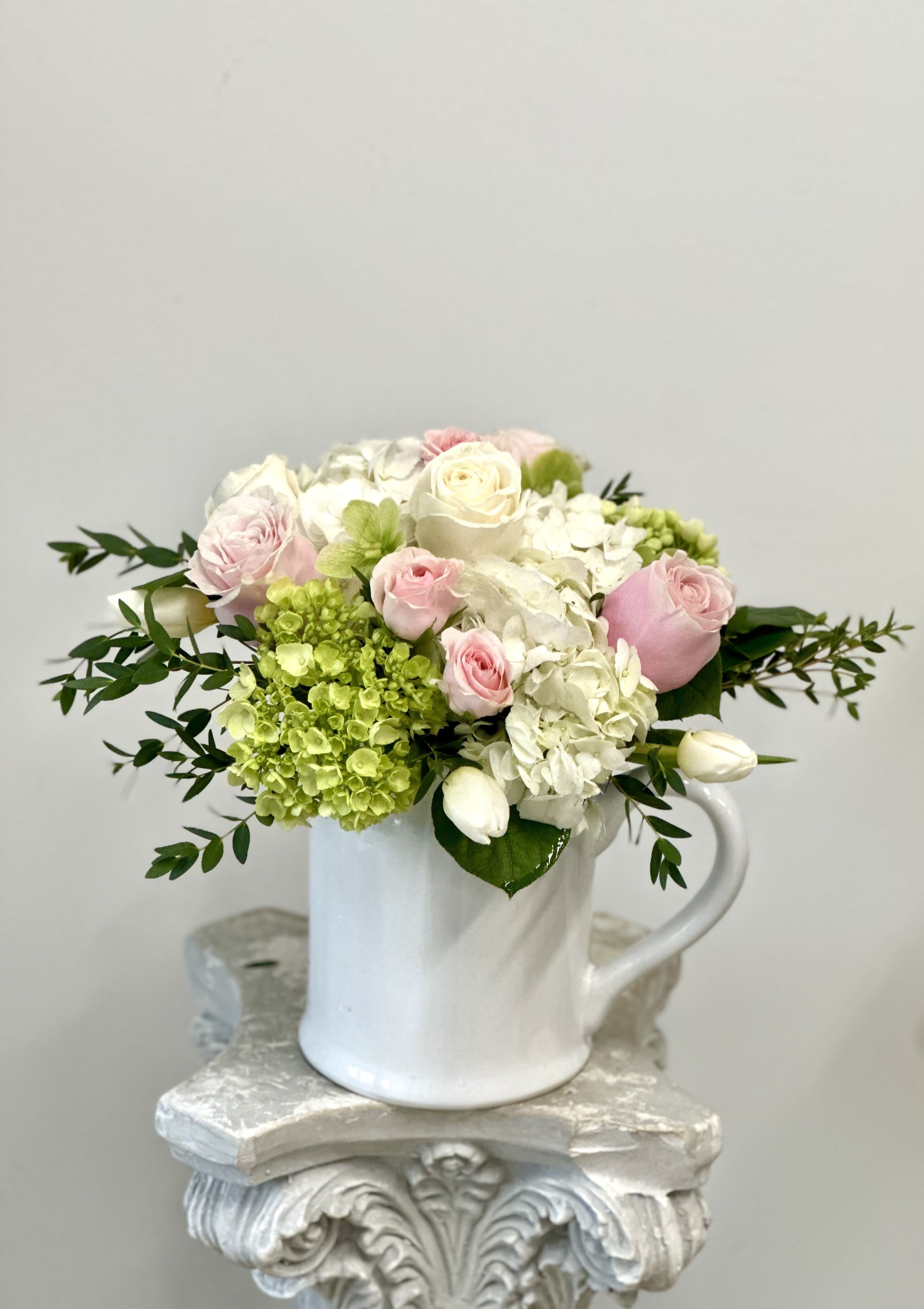 Pink and white roses with hydrangeas in a white mug vase