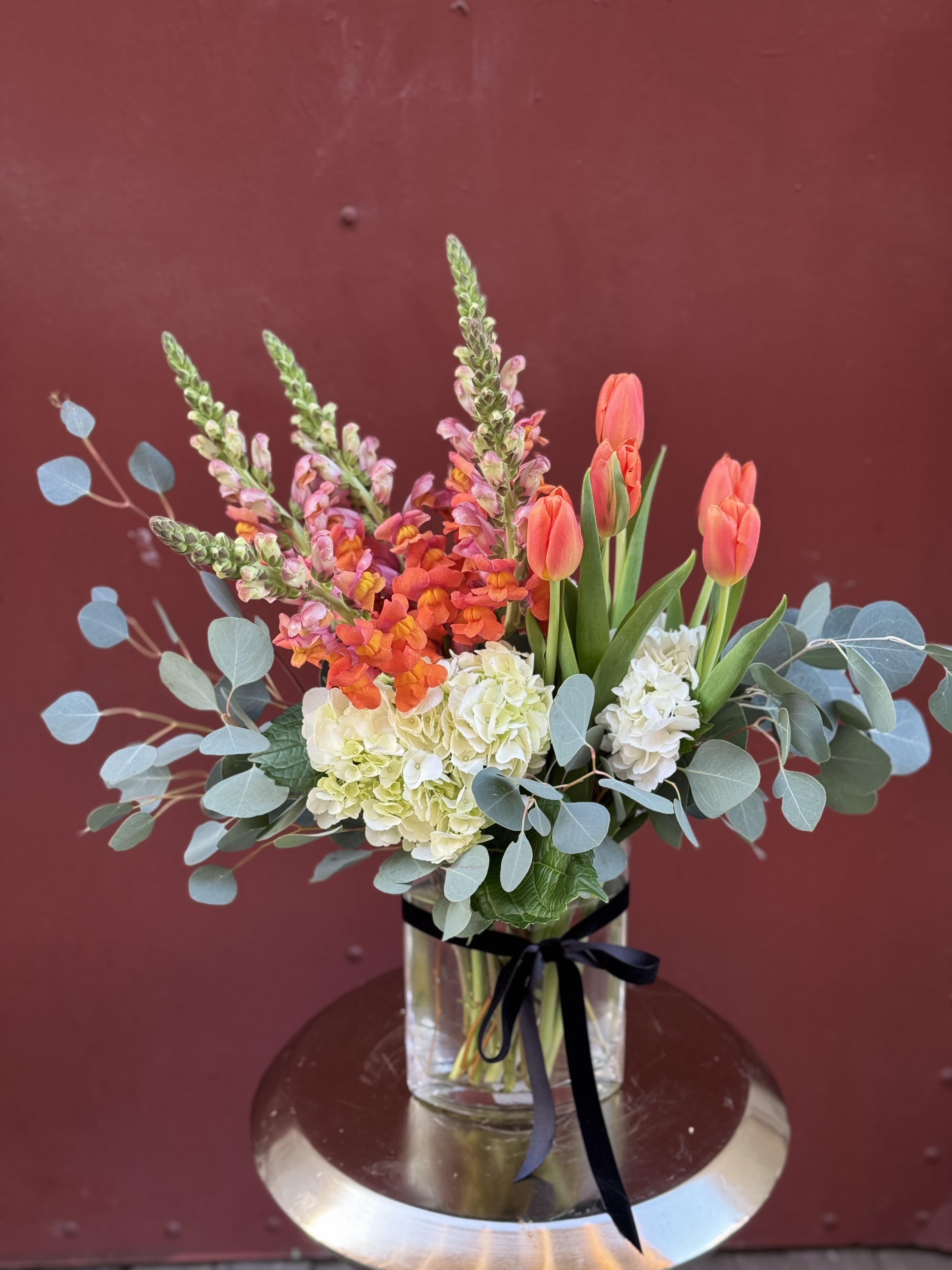 Happiness &amp; Joy  - Inspired by the spirit of joyous orange tones and happiness that flowers create, this arrangement is a lovely balanced arrangement for Mother's Day.  Hydrangeas, Ca grown snap dragons, tulips and eucalyptus.