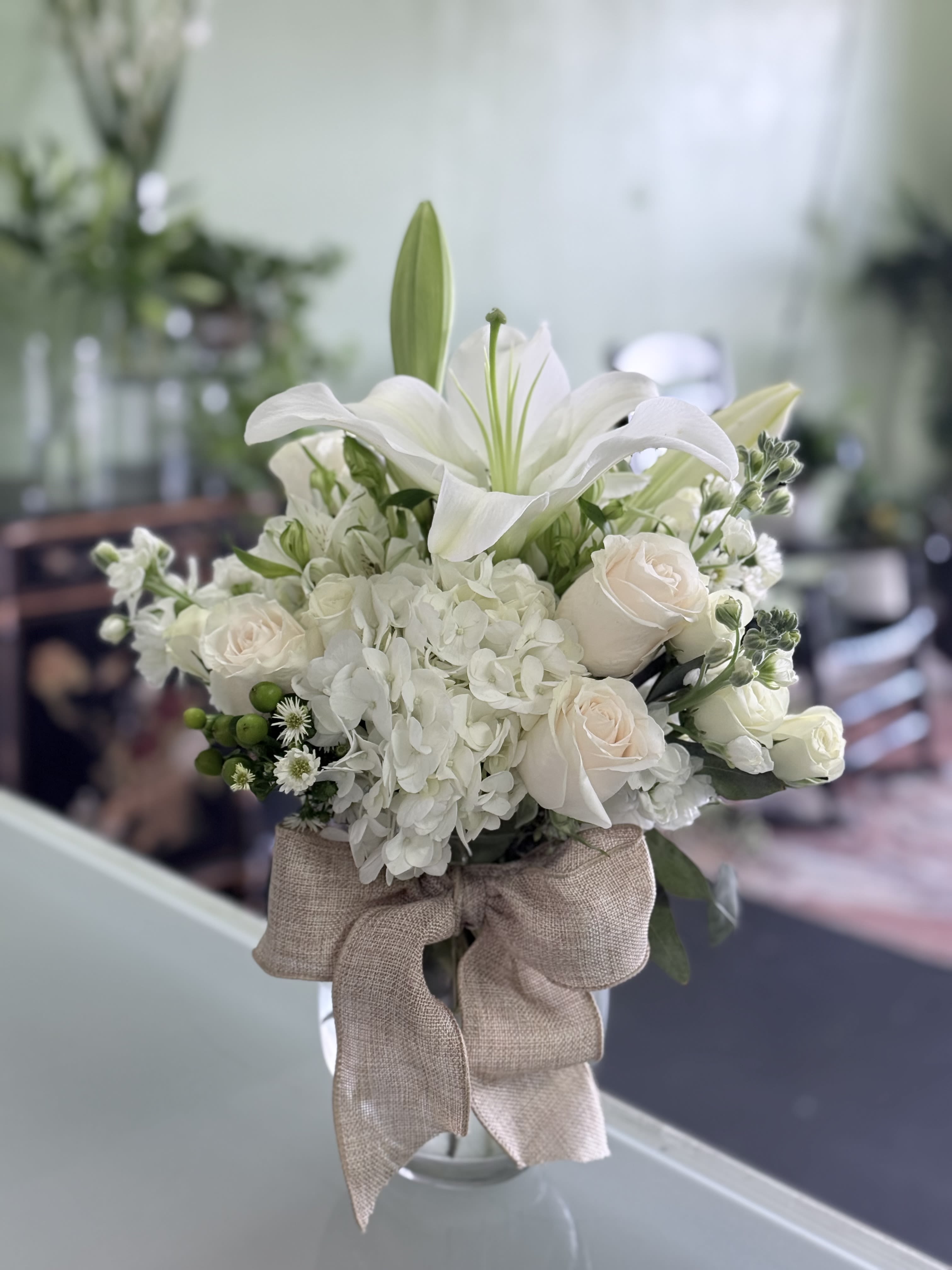 White lily and rose bouquet with hydrangea in a glass vase
