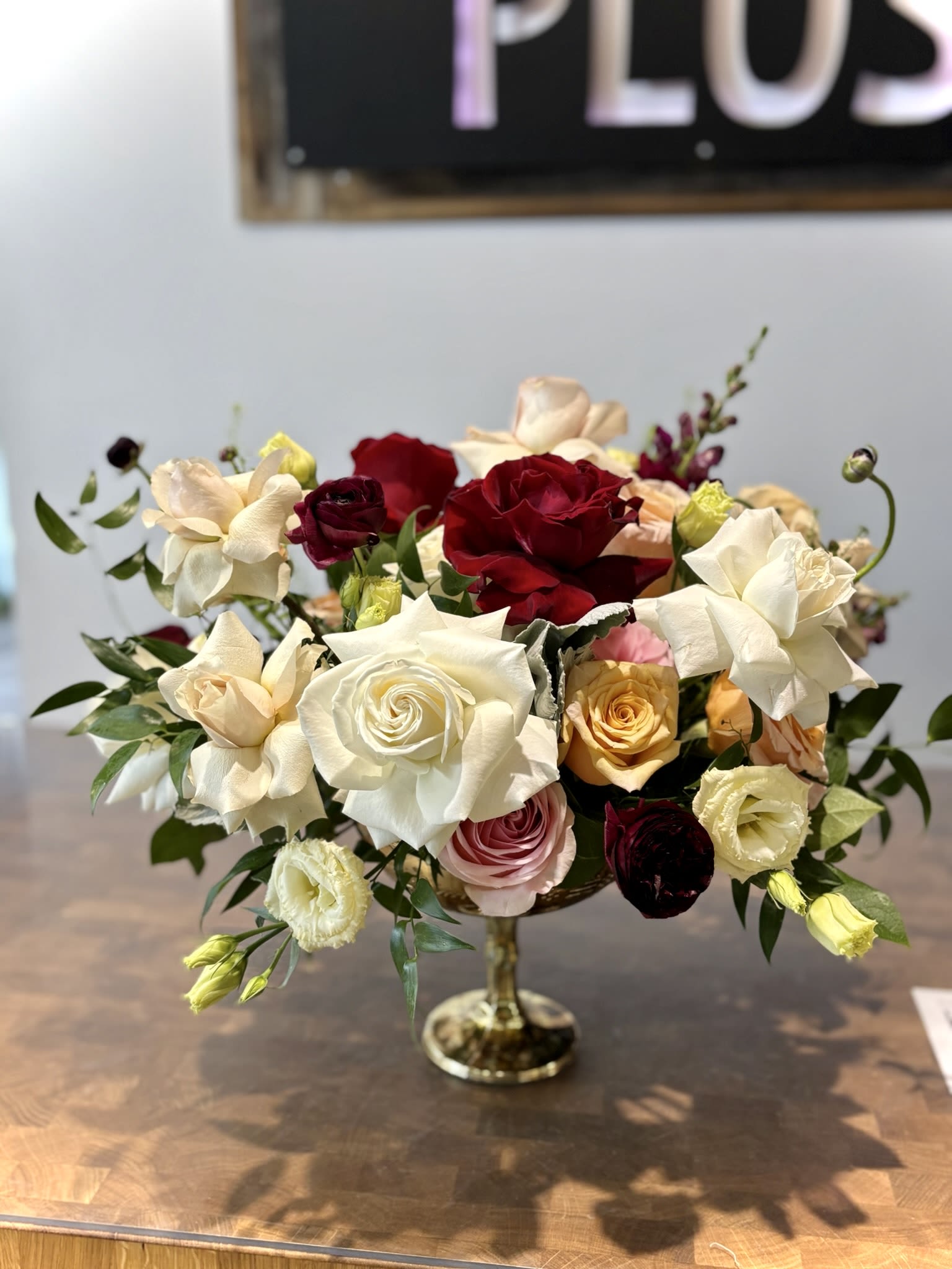 Mixed roses in cream, red, pink, and peach arranged in a glass vase