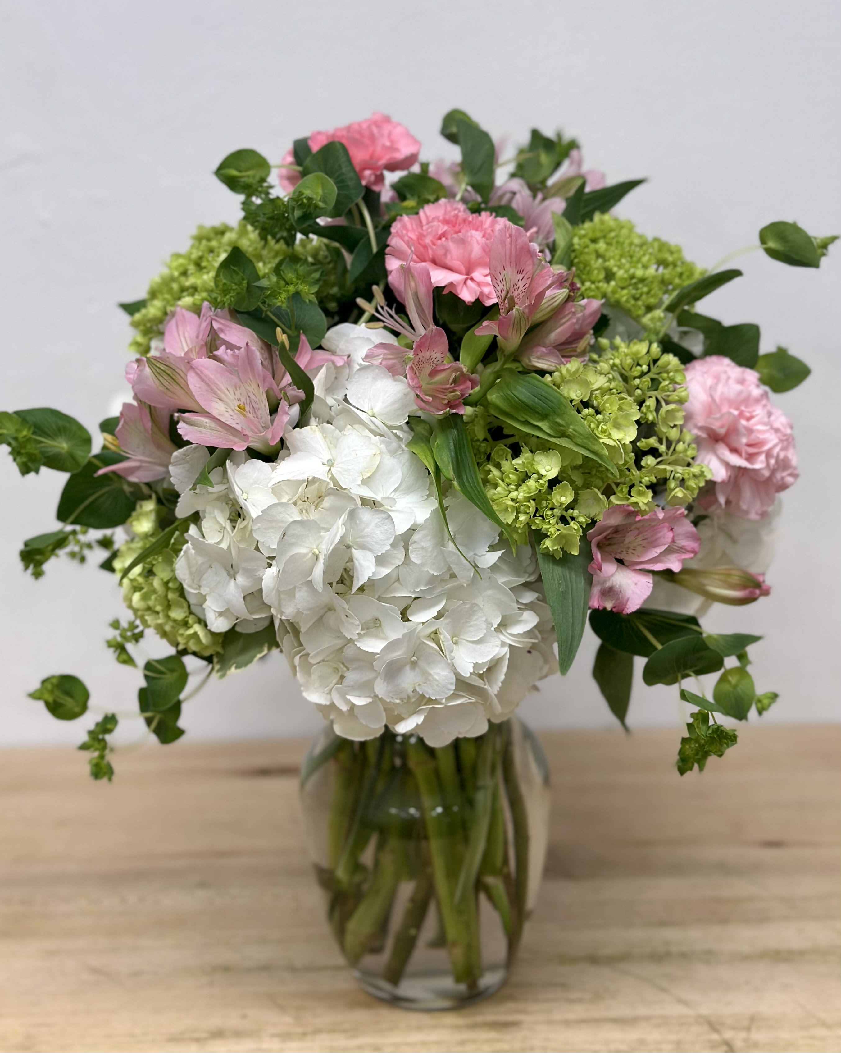 Pink and white flowers arranged in a glass vase