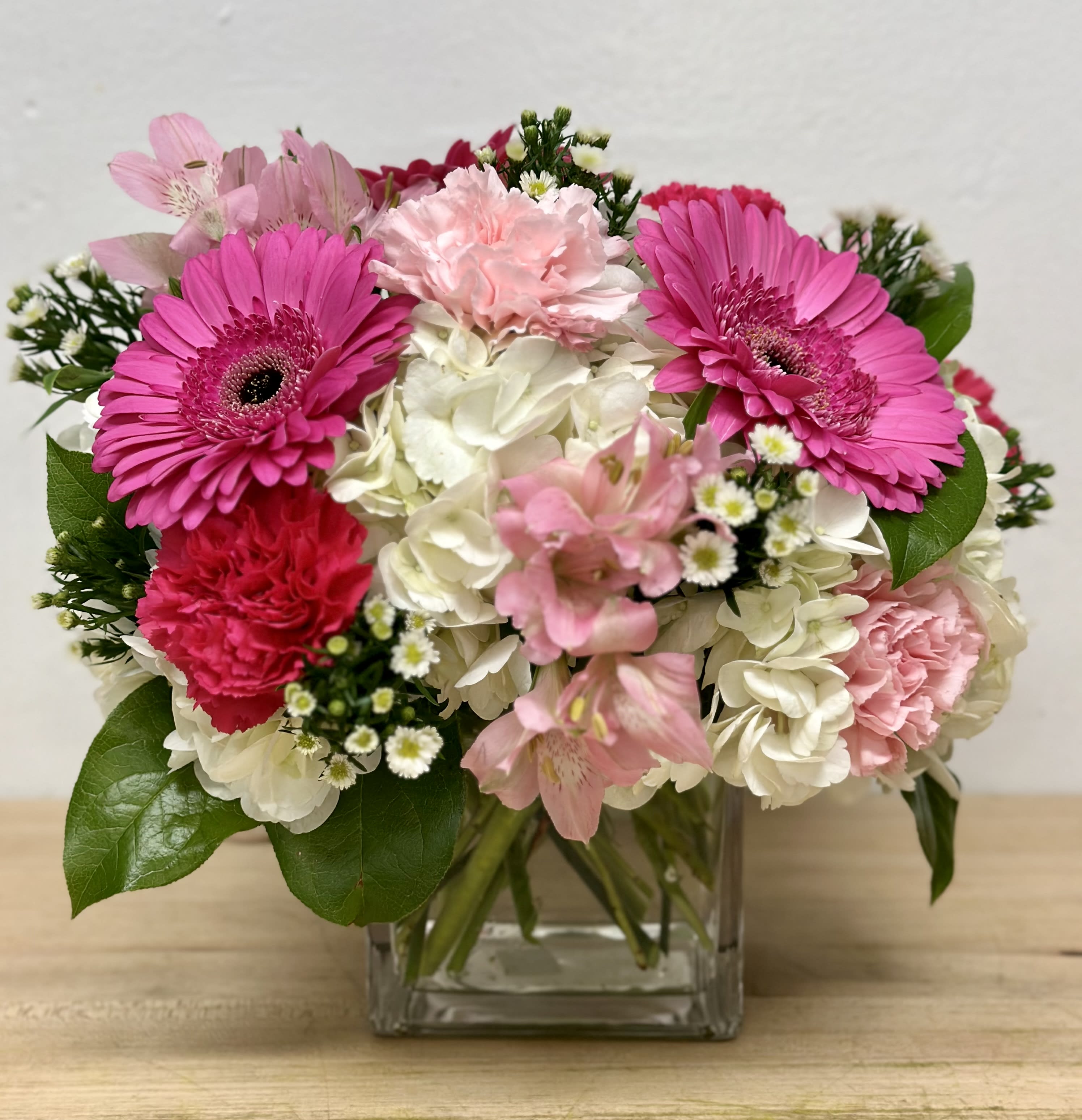 Pink gerberas and carnations in a clear glass vase