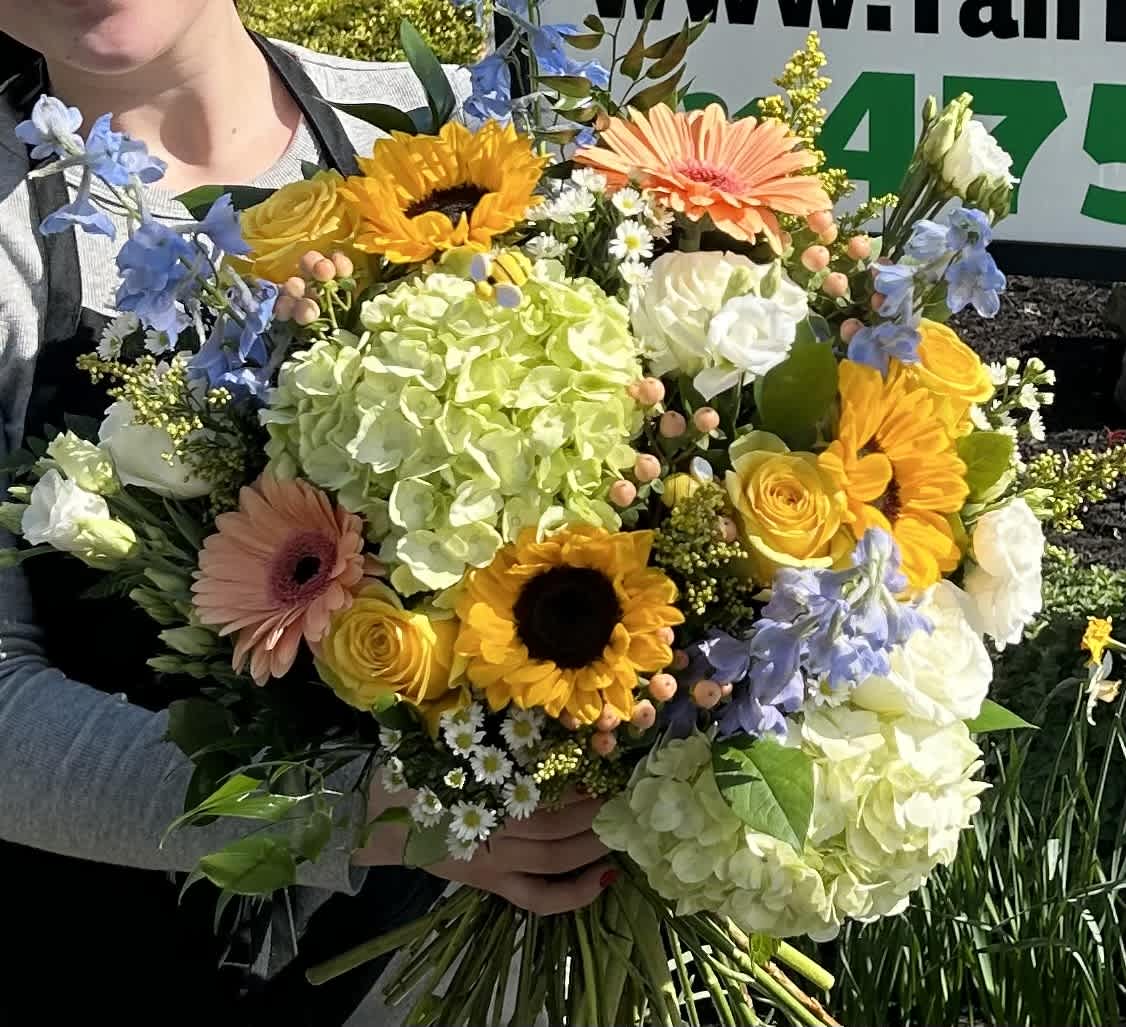 Handheld bouquet with sunflowers, roses, hydrangeas, and gerbera daisies