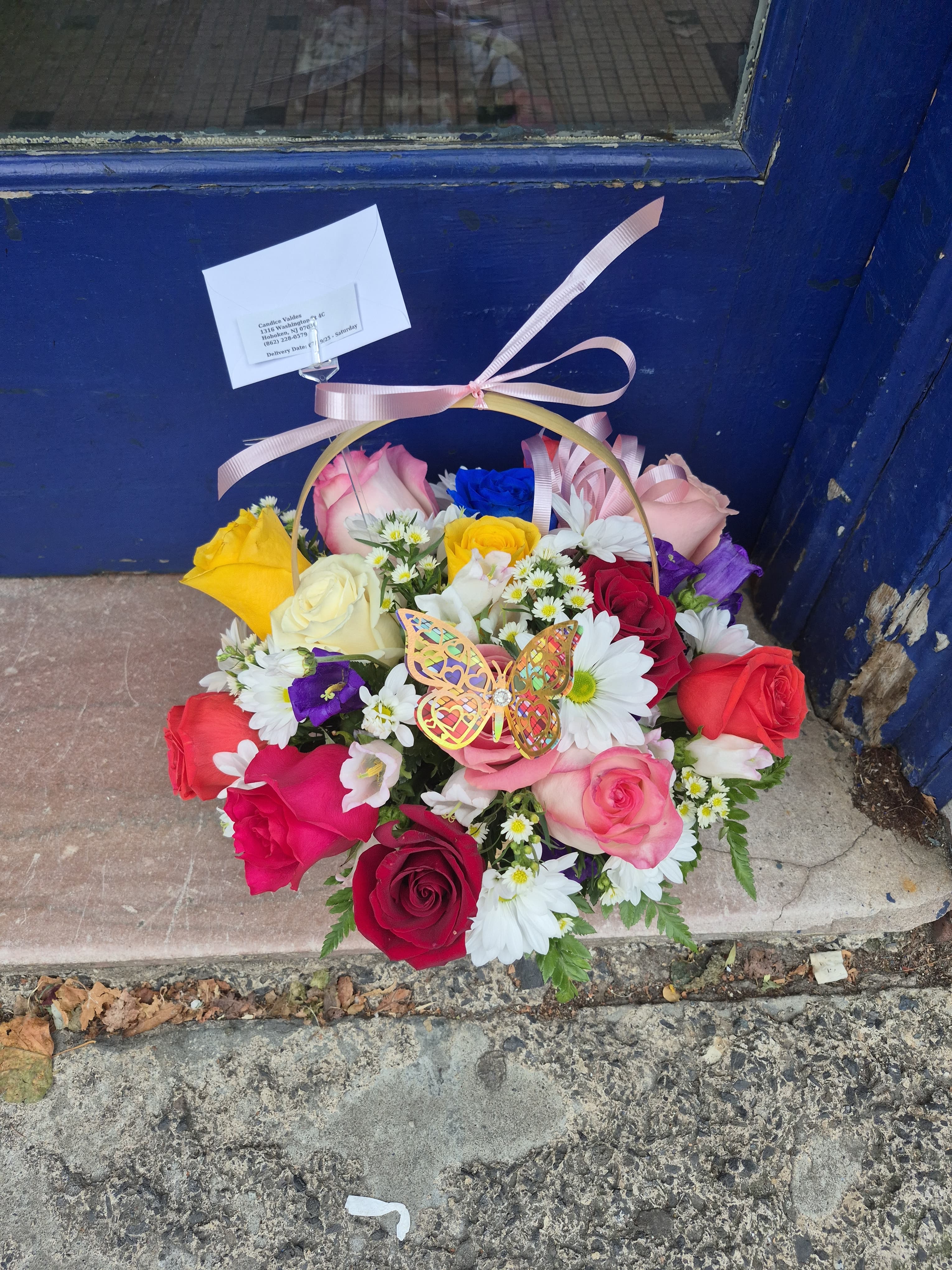 Mixed rose bouquet in a ribboned basket with white daisies