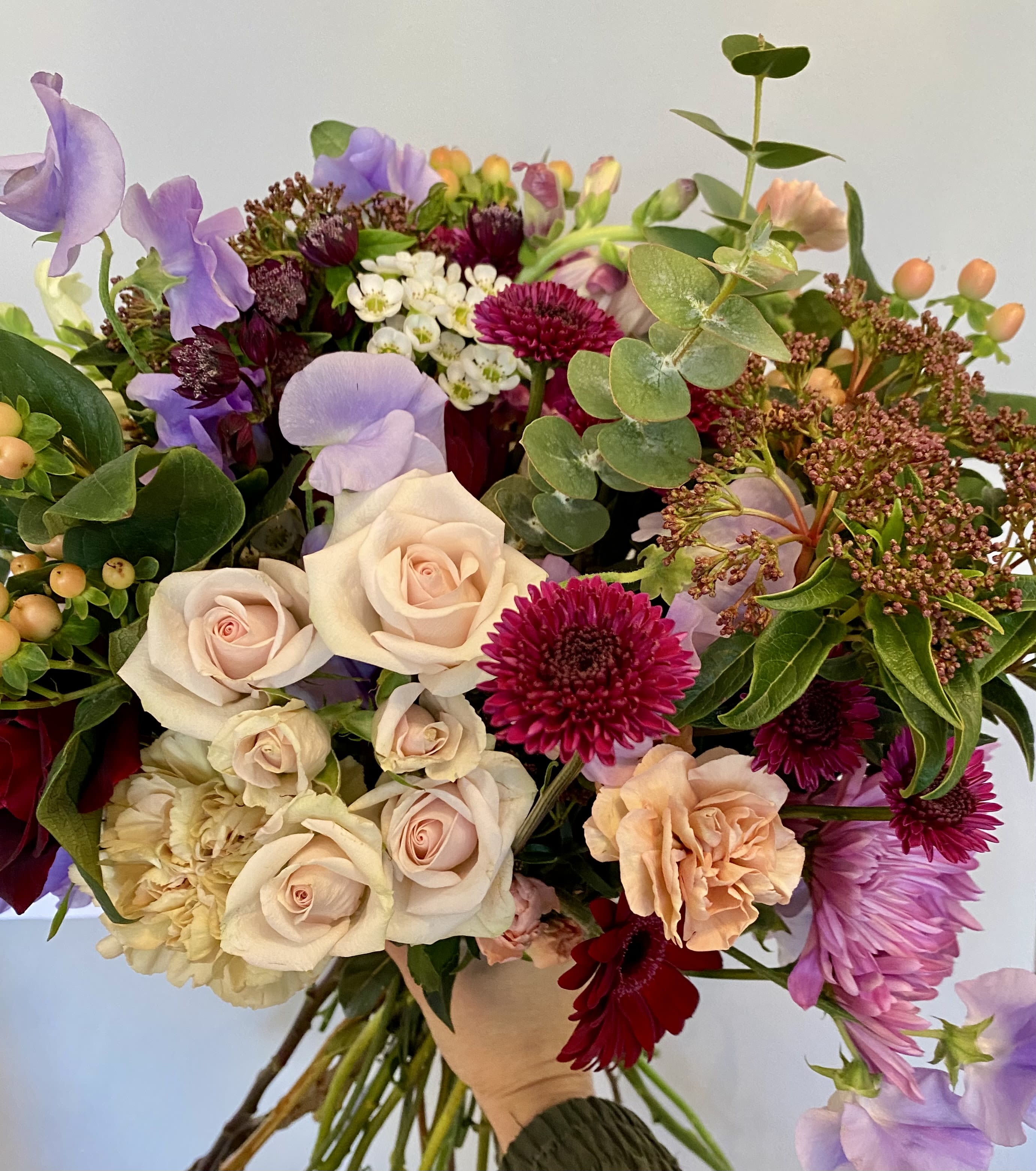 Mixed bouquet with pale roses, purple sweet peas, and magenta blooms