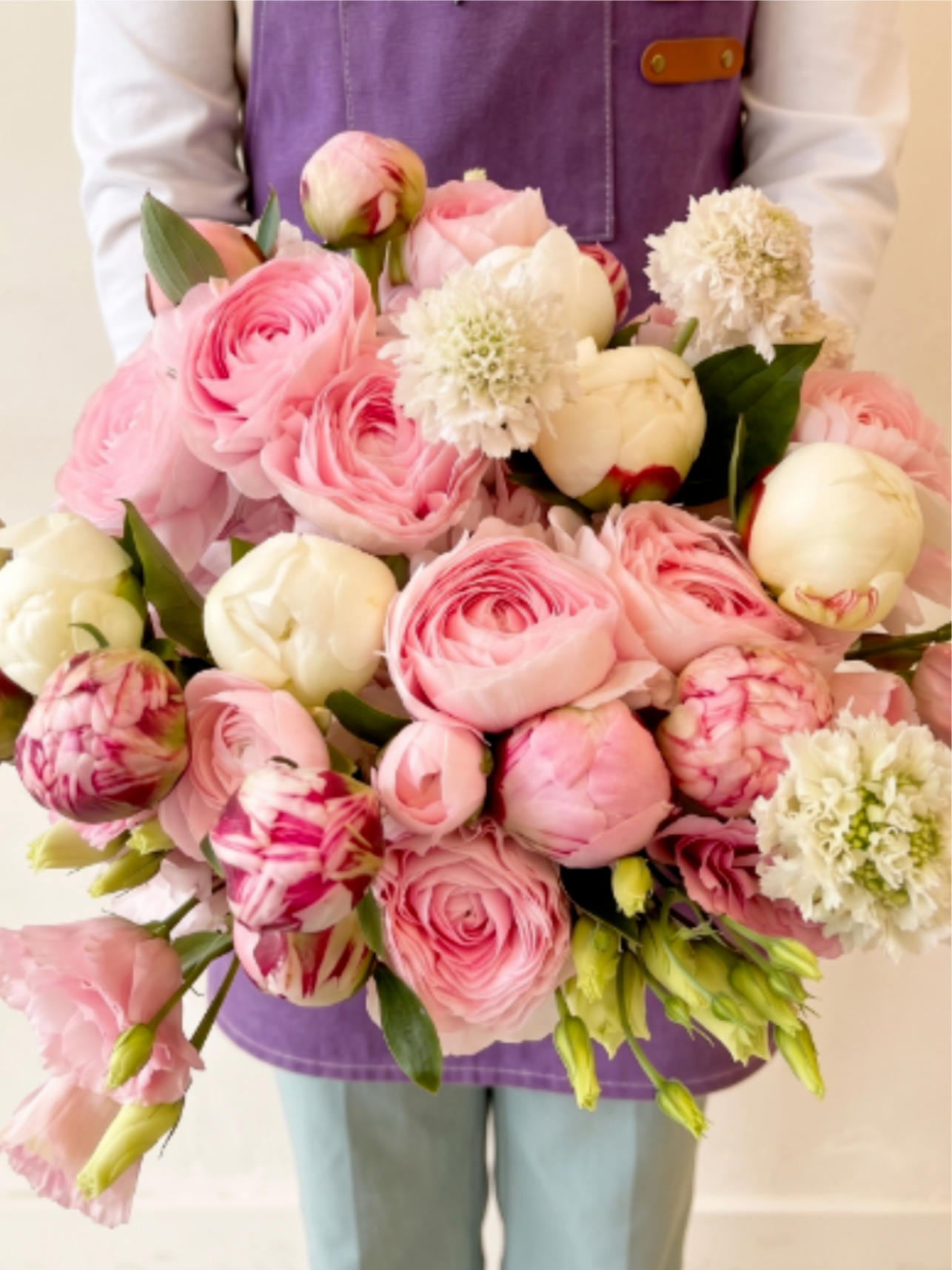 Large bouquet of pink and white flowers held in front of a person