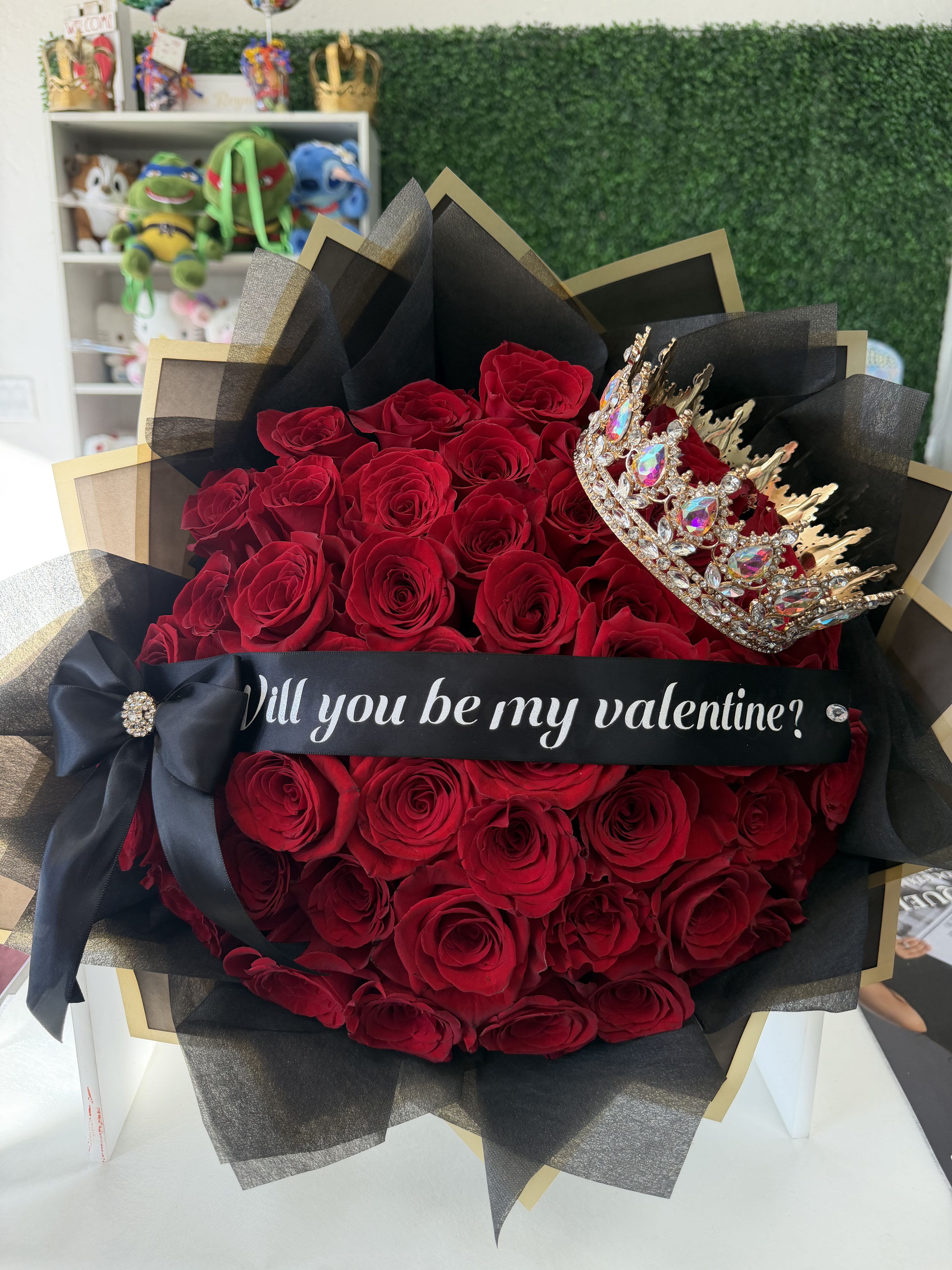 Princess Deluxe Bouquet  - 25 long stem red roses wrapped in our black with gold flower paper, Topped with a custom ribbon of your choice and crown, if you have an questions about customizing your bouquet feel free to call our store !