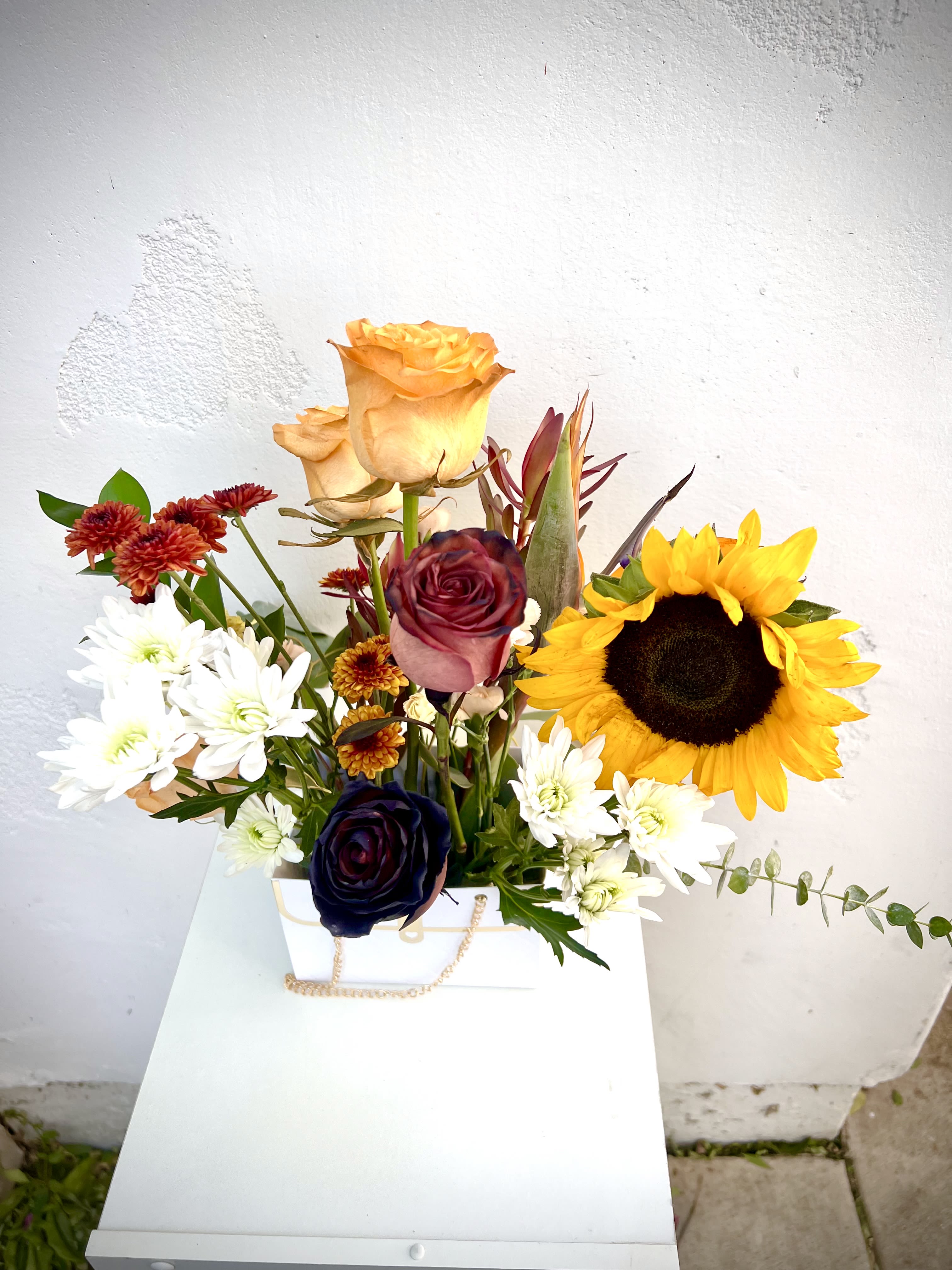 Mixed bouquet with sunflowers, roses, and white daisies in a white box