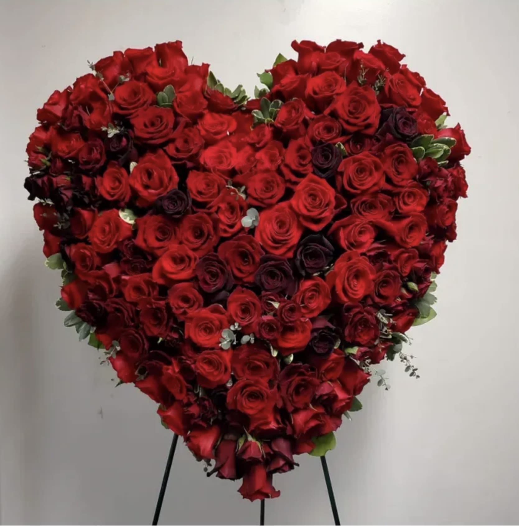 Heart-shaped arrangement of red roses on a stand
