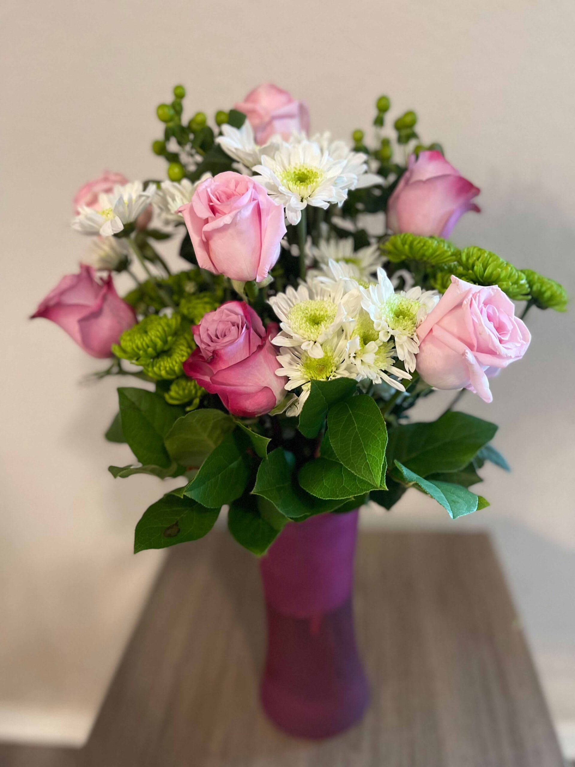 Ava - Delightful bouquet of 12 pink, purple and white roses, white and green chrysanthemums ,green hypericum blooms and fresh greens on a tall pink vase.