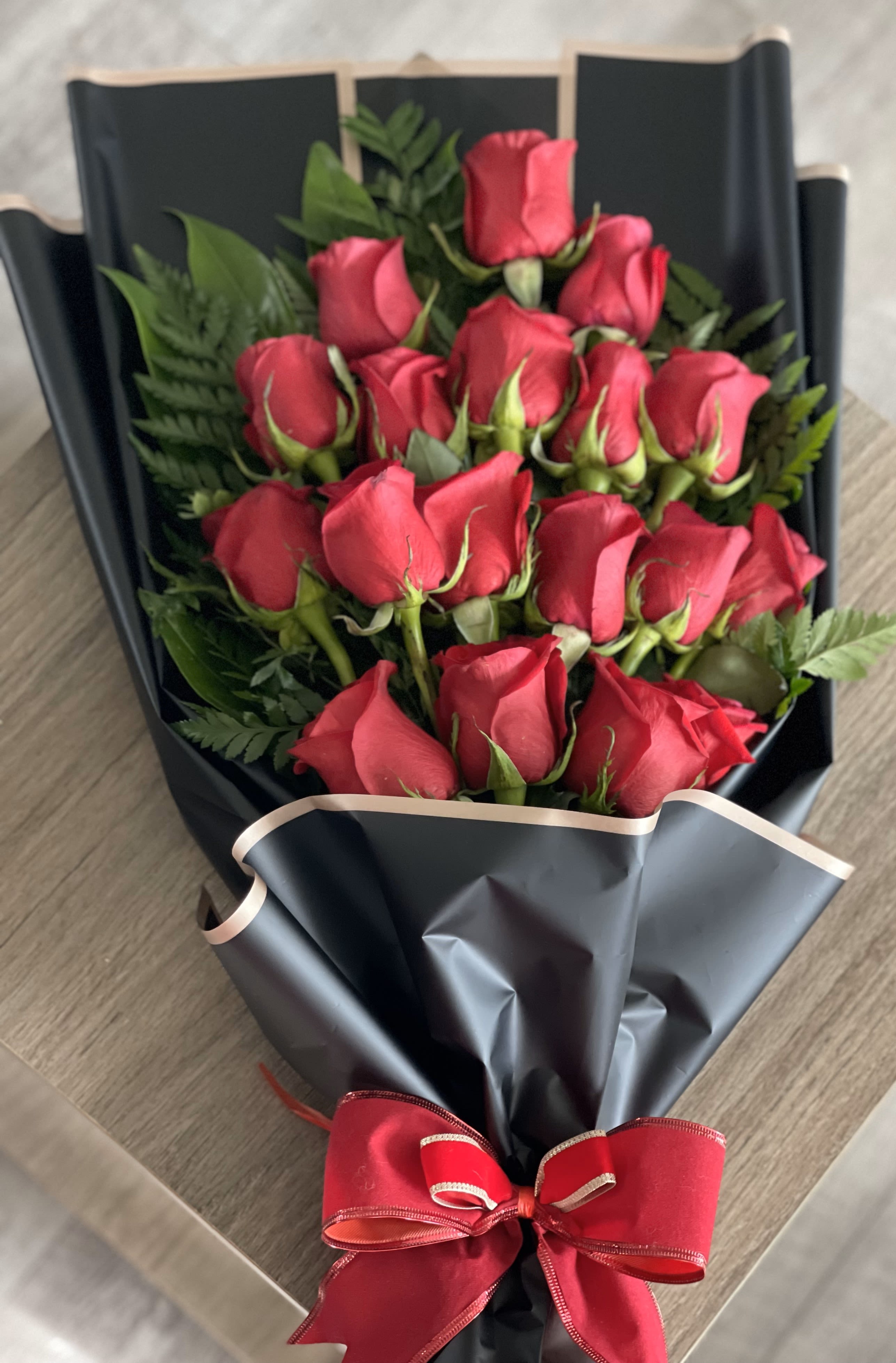 Bouquet of red roses wrapped in black paper with a red ribbon