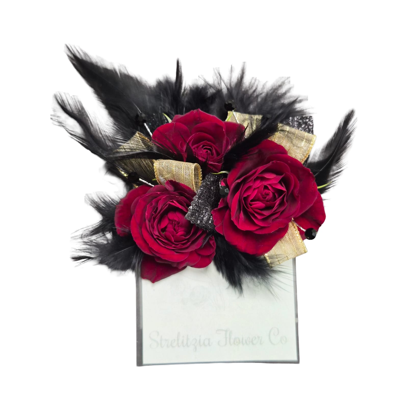 Gold &amp; Glam Pocket Boutonierrie - Three deep red spray roses clustered tightly create a bold, fashion-forward pocket boutonniere that makes a striking statement for prom or any formal night. Black feathers fan around the blooms to add dramatic texture while metallic gold ribbon and a small glittery black accent bring a couture touch-perfect for someone who prefers romantic color with an unconventional edge.  Designed to slide neatly into a men's jacket pocket, this pocket boutonniere pairs rich reds, inky black feathers, and touches of gold and white from the spray roses' highlights for contrast.