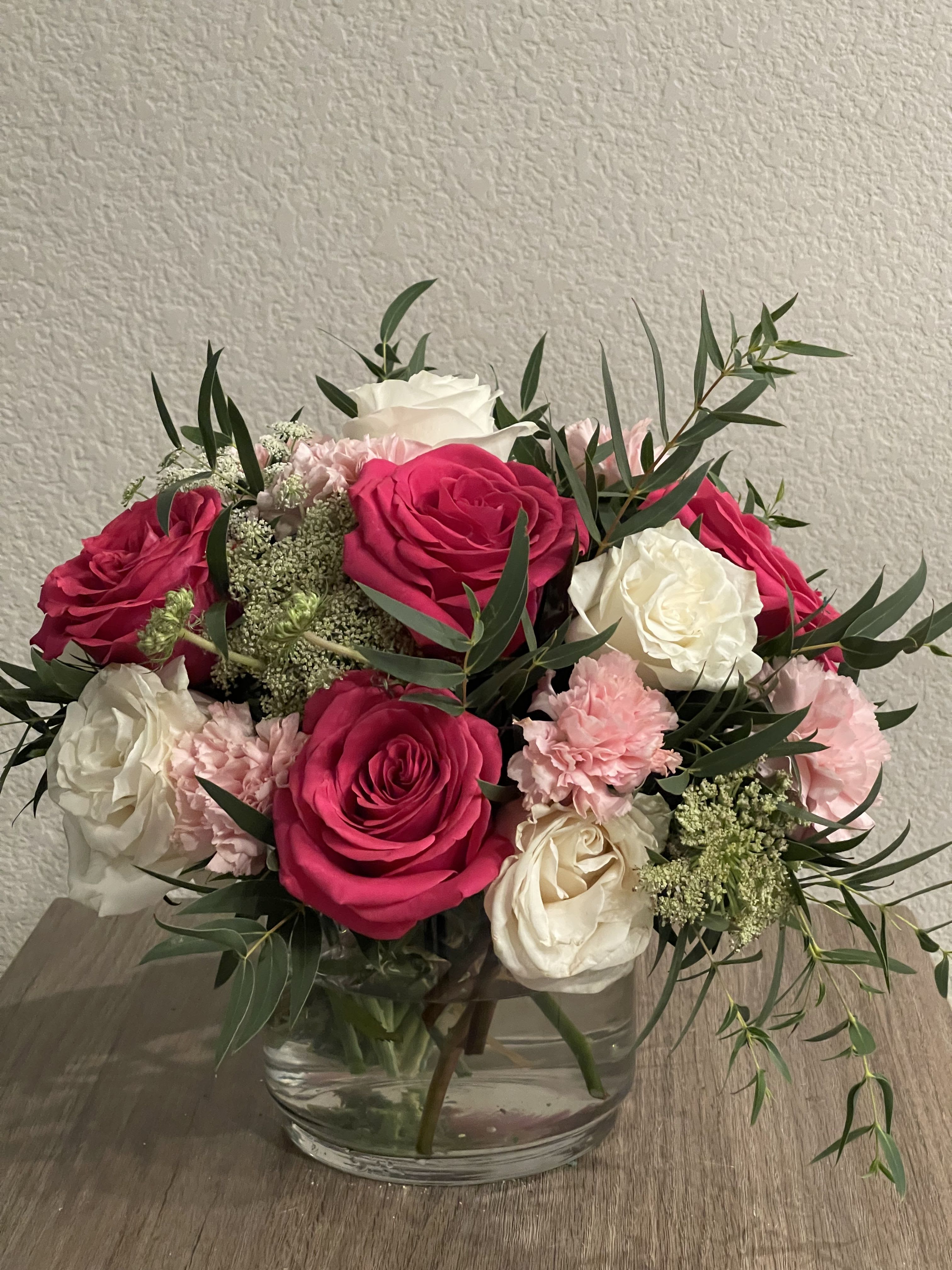 Pretty Petals - These gorgeous roses flaunt their incredible flashy pedals. White and fuchsia premium roses, pink carnations, queen lace flowers and assorted greenery to create this astonishing creation. Everything is displayed on a glass cylinder vase.