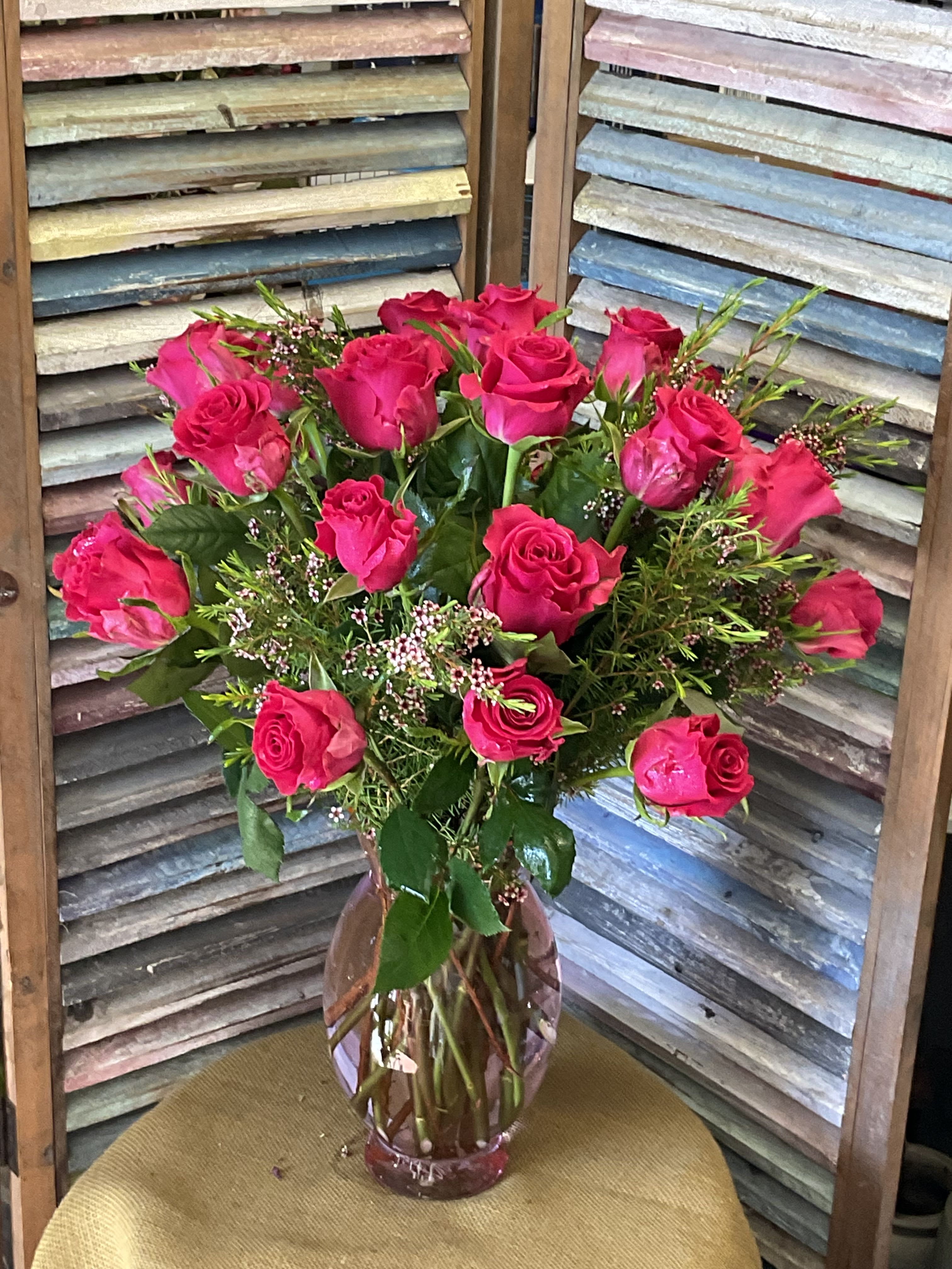 Hot Pink Rose Bouquet  - Hot pink roses arranged tightly in a pink glass vase with white filler blooms and green accents.