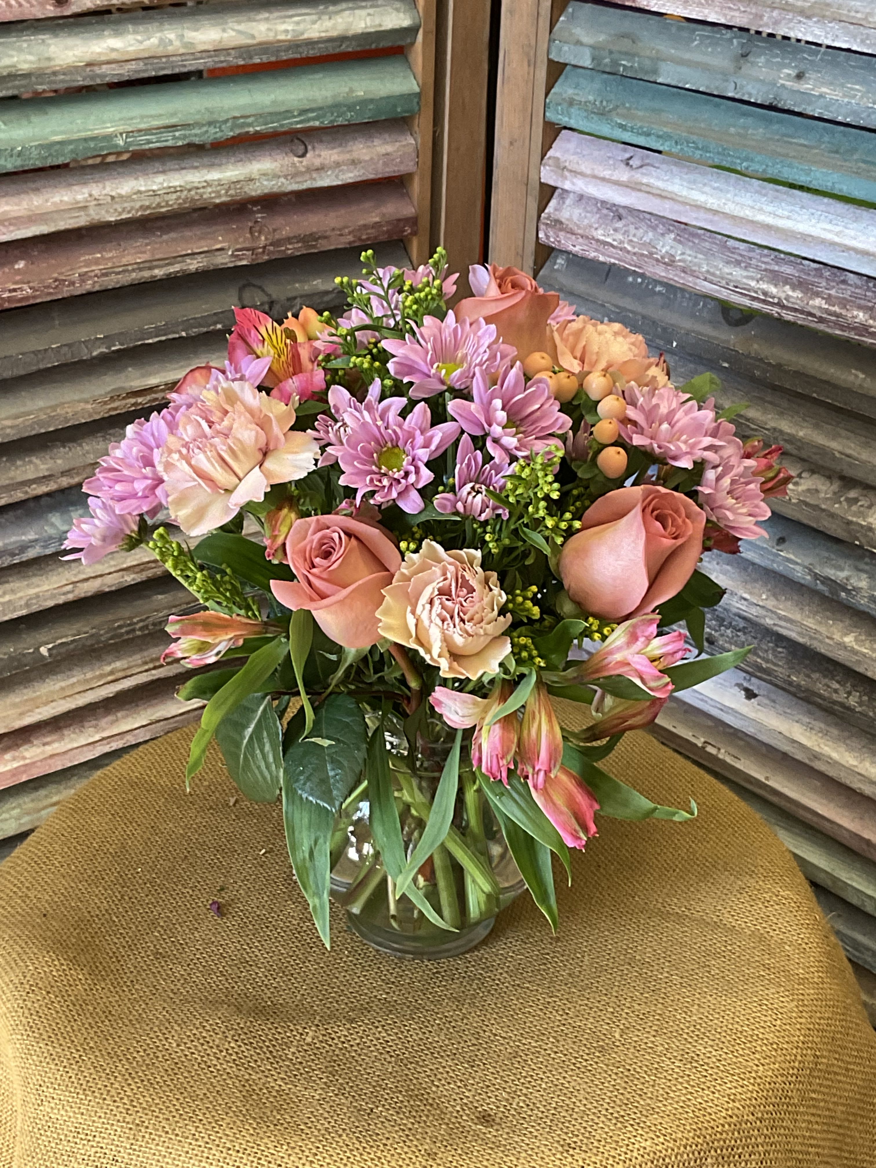 26-125 - Full rounded bouquet of pink, peach, white blooms - roses, carnations, mums, alstroemeria in a clear vase.
