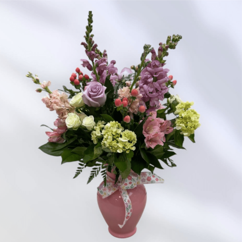 MD63 Pastel Wish - Soft, romantic, garden-style blooms in pinks, lavenders, and white this tall showy pastel colored vase is filled with roses, snapdragons, alstroemeria and hydrangea is finished with a ribbon, perfect for gifting.