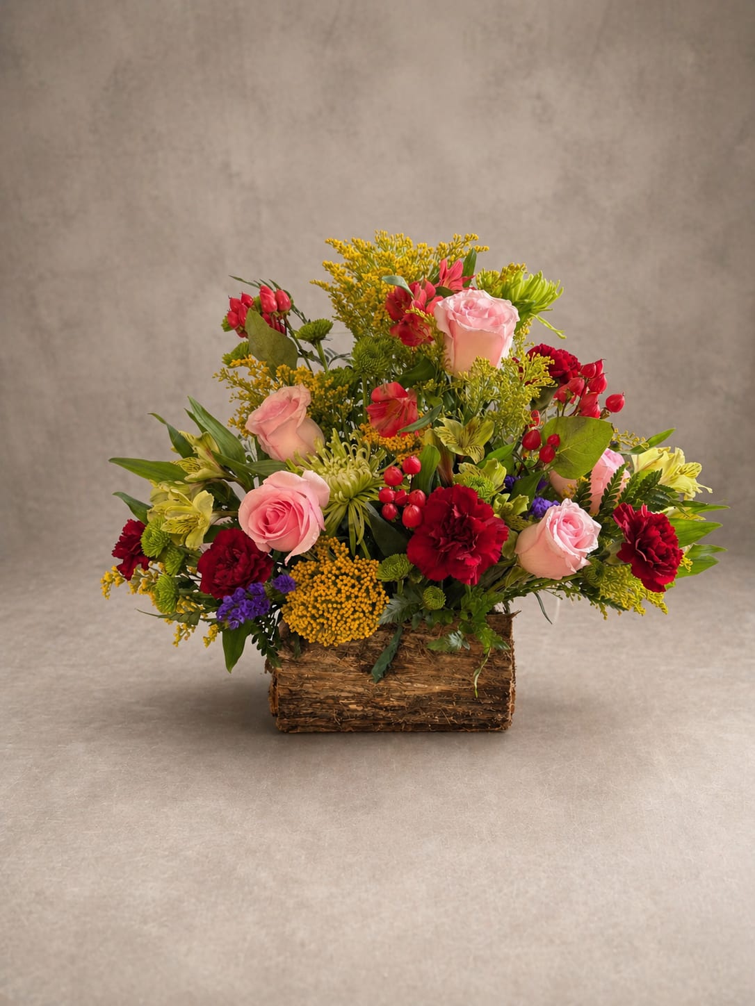 still with you - Cemetery Log Arrangement A timeless tribute for those who deserve to be remembered beautifully. Our cemetery log arrangements are handcrafted in a rustic natural wood log container, designed to sit gracefully at a graveside without tipping or shifting. Each arrangement is filled with an abundant mix of seasonal blooms — lush garden roses, rich carnations, delicate alstroemeria, and accents of goldenrod and berries — creating a full, traditional display that honors your loved one with dignity and warmth. Weathered and rooted in nature, the cemetery log is as enduring as the memories it marks. Available in a variety of color palettes to suit any sentiment — from soft and gentle to bold and vibrant.