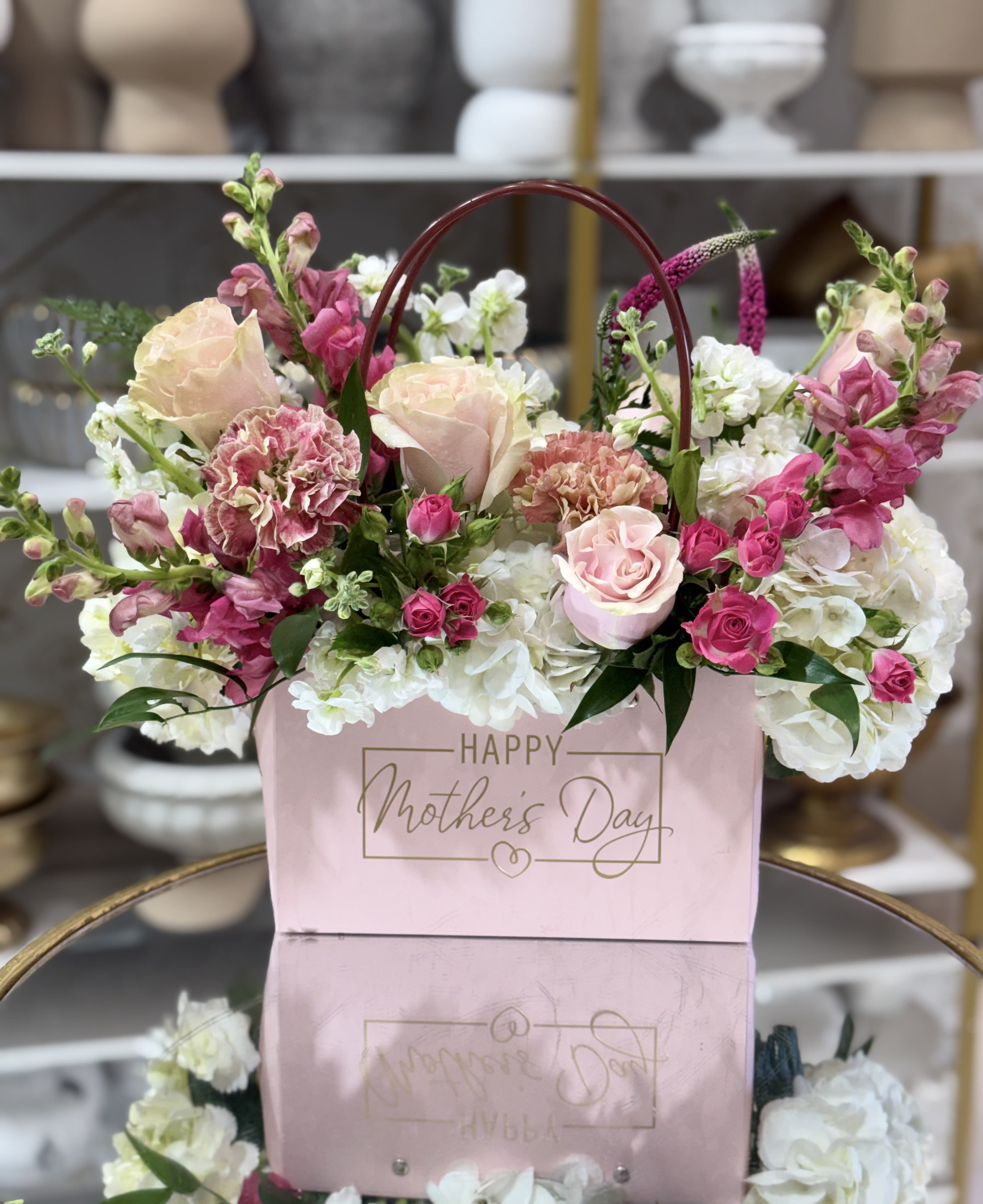 With Love For Mom  - Soft blush roses and tall pink snapdragons rise above ruffled white hydrangeas in a giftable arrangement made for Mother's Day and any moment you want to celebrate her. This flower arrangement for Mom is presented in a pink gift bag with a curved arched handle and a gold "Happy Mothers Day" message on the front, giving it a hand-delivered, boutique feel that immediately says "you're thought of."  