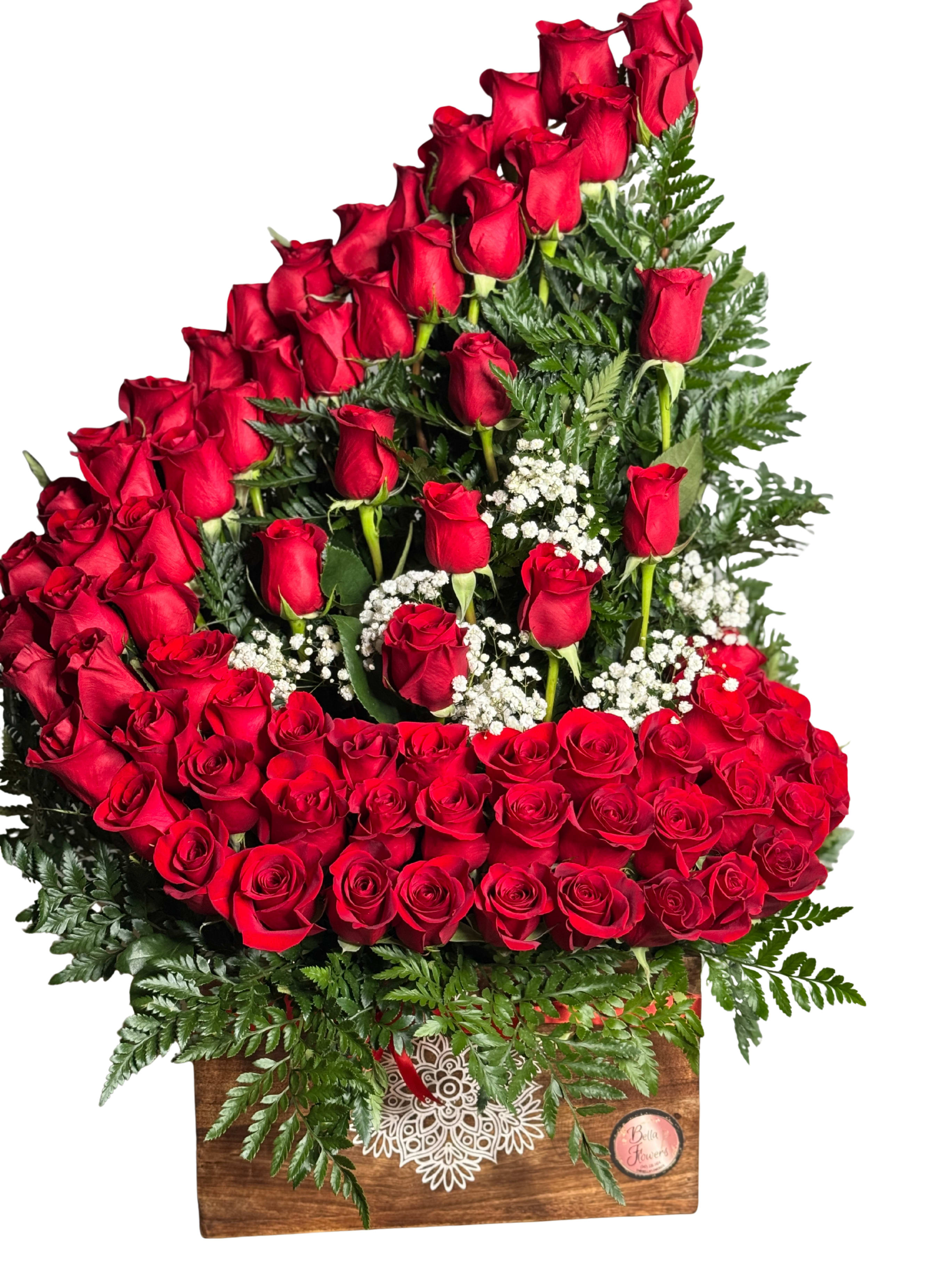 Majestic Love - A lush cascade of deep red roses arranged tall and dense-this flower arrangement is a romantic birthday bouquet or anniversary roses gift that makes the person you're thinking of feel truly cherished. White filler blooms peek through the red, and fern-like greenery softens the silhouette for a classic, love-themed presentation that also works beautifully for Valentine's Day or to mark a special celebration.  Seventy-five red roses are layered into a cascading display and set in a rustic wooden box finished with a decorative printed emblem and ribbon for a handcrafted, gift-ready look. Sprays of small white filler flowers and verdant fern textures add contrast and depth while the compact box keeps the arrangement sturdy and easy to present.  Perfect for an anniversary, a bold romantic gesture, or to say "I love you" without words-the Majestic Love arrangement arrives ready to display. For best enjoyment, keep stems in fresh water and away from direct heat; order early for delivery on your chosen date to ensure it arrives at peak bloom.