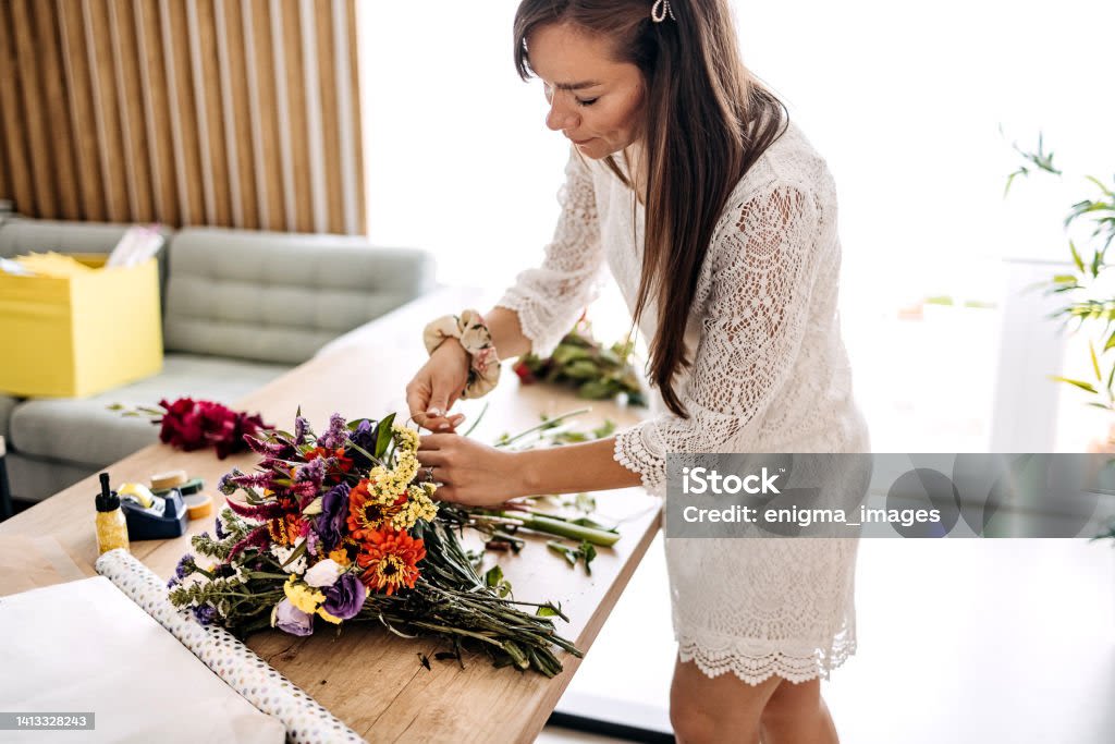 Woman arranging a colorful bouquet on a table