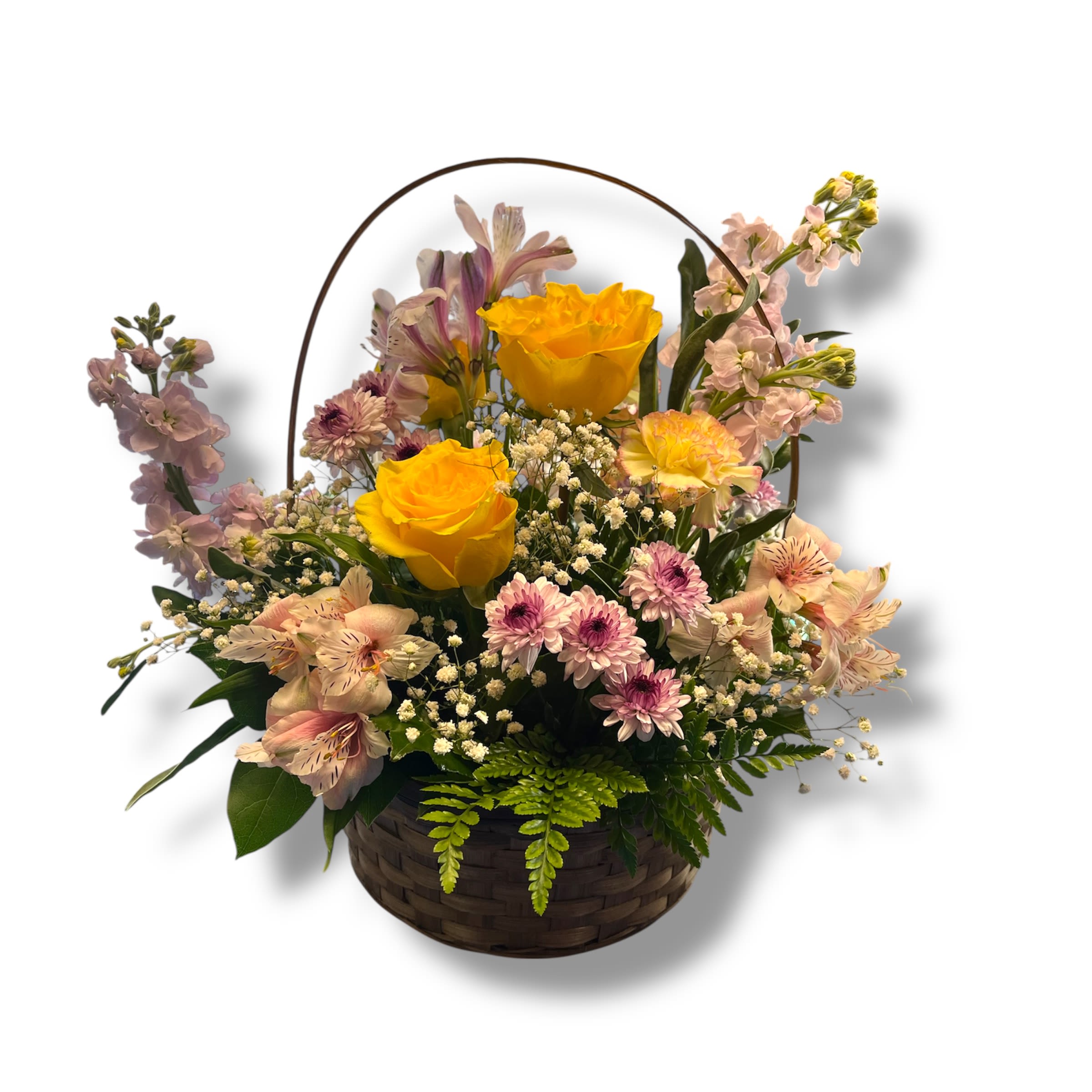 Mom's Blooming Basket  - Bright yellow roses take center stage in this mom's blooming basket, creating a sunny focal point that instantly lifts the spirit-perfect as a birthday bouquet, a thank-you gift, or a thinking-of-you arrangement for Mother's Day. The cheerful spring palette of yellow, pink, white, and purple reads as fresh and gentle; the wicker basket with its curved handle gives the gift a hand-delivered, homey feeling that will make the person you're thinking of feel truly seen.  This hand-gathered basket includes yellow roses, stock, lavender-and-white alstroemeria, lavender pom chrysanthemums, yellow carnations, and a touch of wax (or baby's breath) plus lemon leaf and leatherleaf greenery for texture. Lavender stock-like spikes and a few purple-toned accents add vertical interest while small white filler blooms and daisy-like flowers soften the composition. The arrangement's woven basket and arched handle make it an easy, ready-to-present gift; light daily watering  will help blooms stay vibrant.