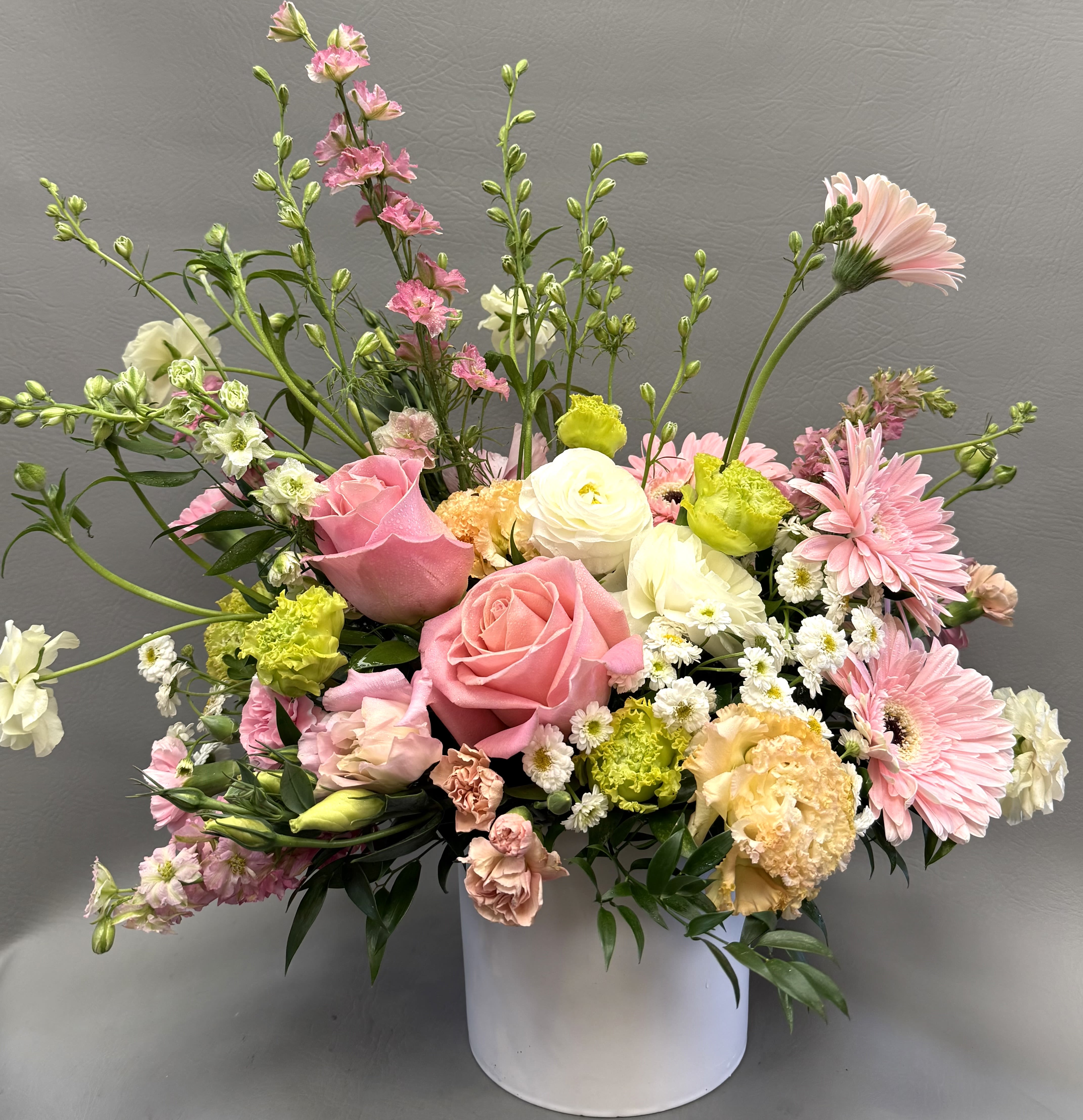 Spring Awakening  - This is a loose, garden-style floral arrangement designed with a natural, airy feel and soft pastel colors. The composition has an asymmetrical, meadow-inspired shape with taller stems extending upward to create movement and height.