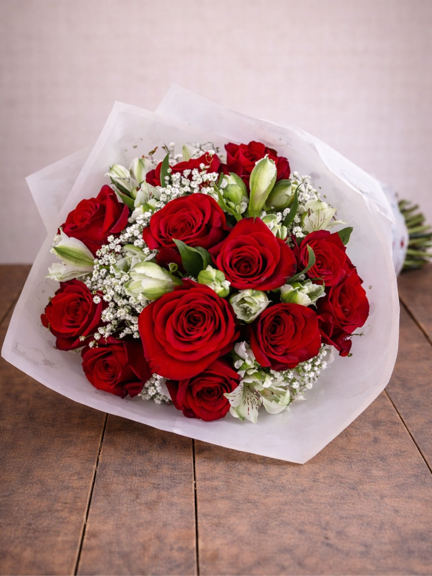 Bouquet of red roses with white filler flowers wrapped in white paper