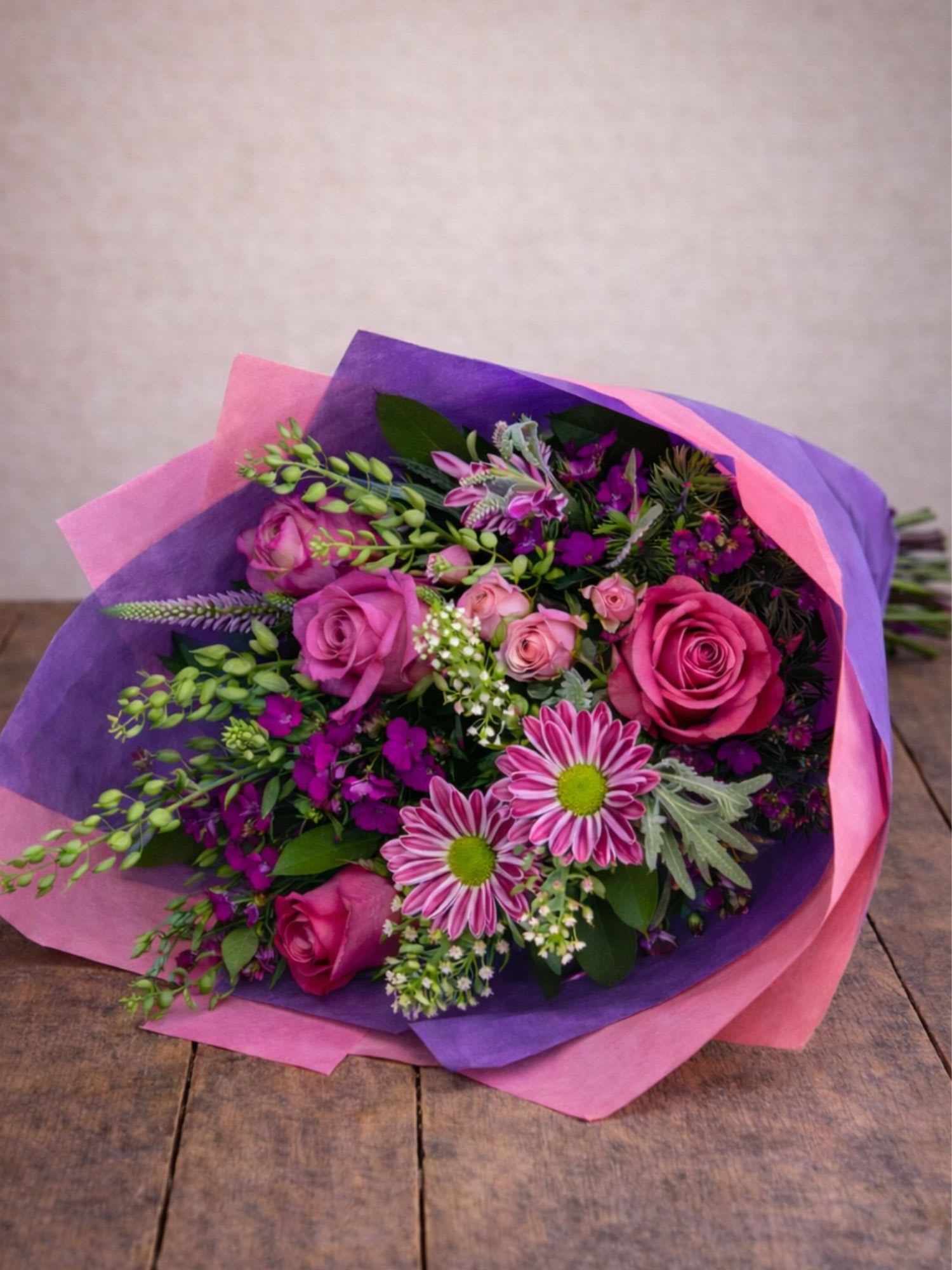 Bouquet of pink roses and purple flowers wrapped in pink and purple paper