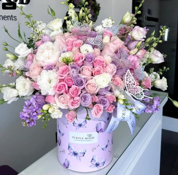Large pastel bouquet of pink, lavender, and white roses in a butterfly-print box