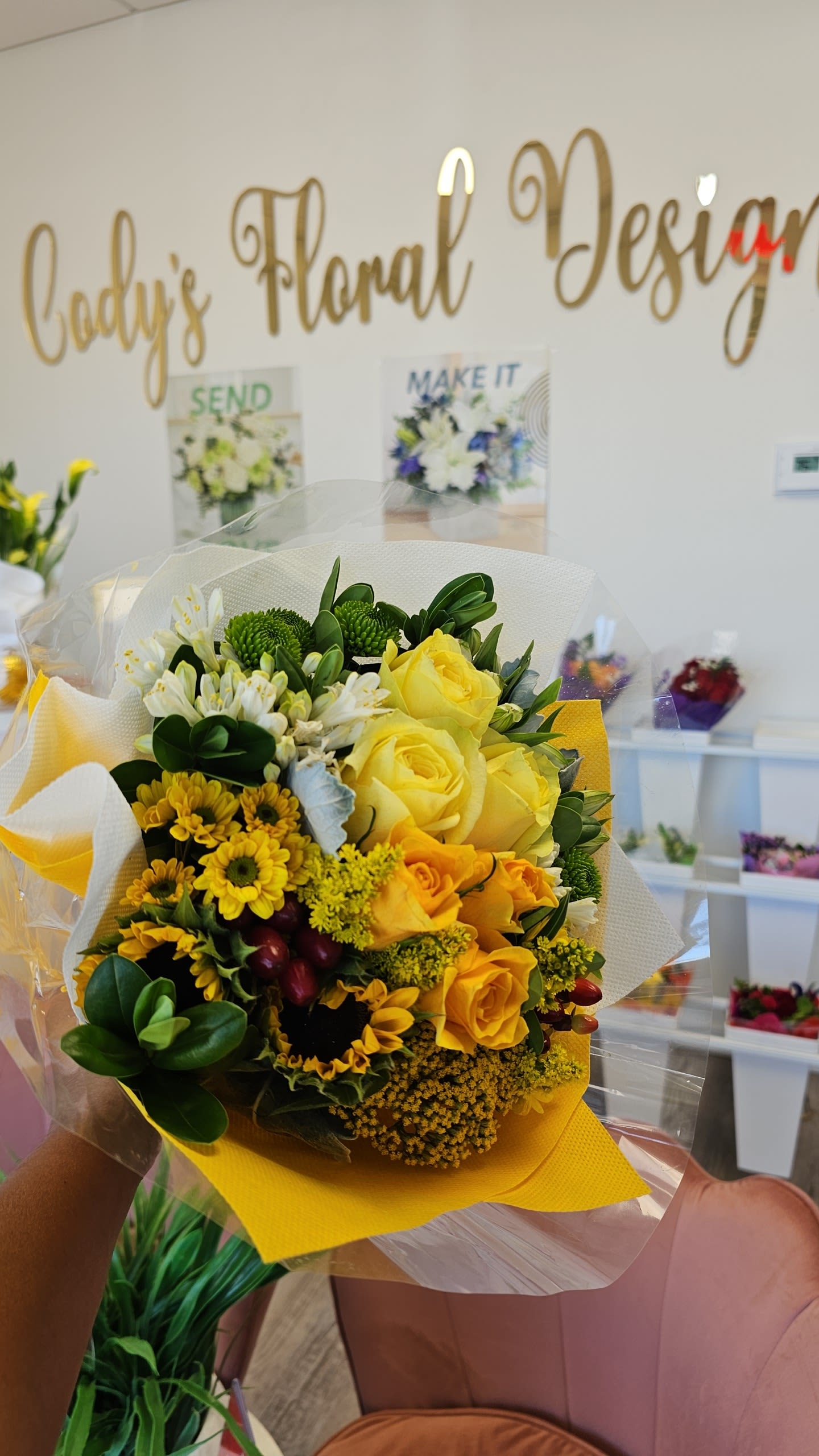 Yellow rose bouquet with white flowers and green accents wrapped in paper
