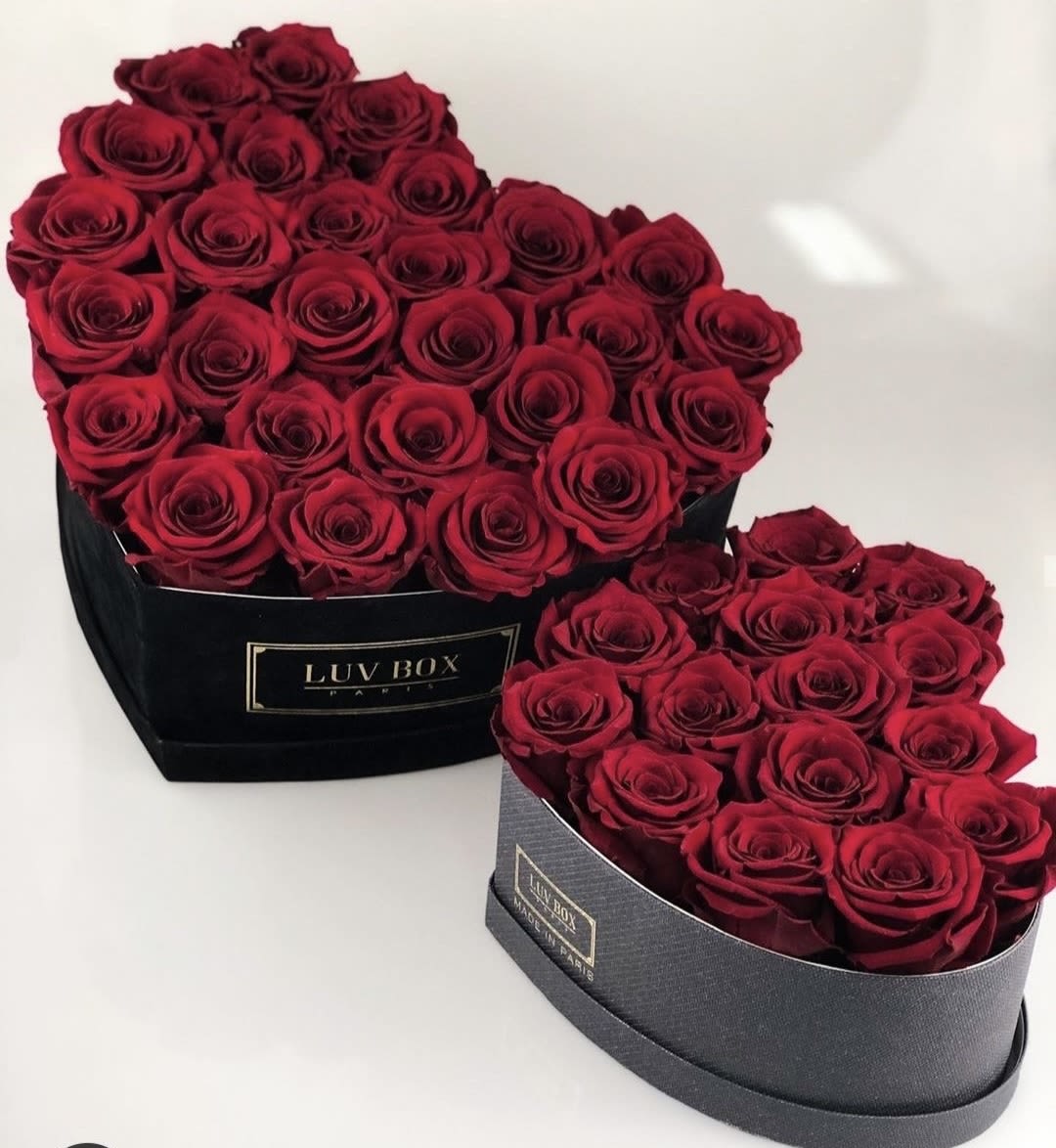 Two heart-shaped boxes filled with red roses