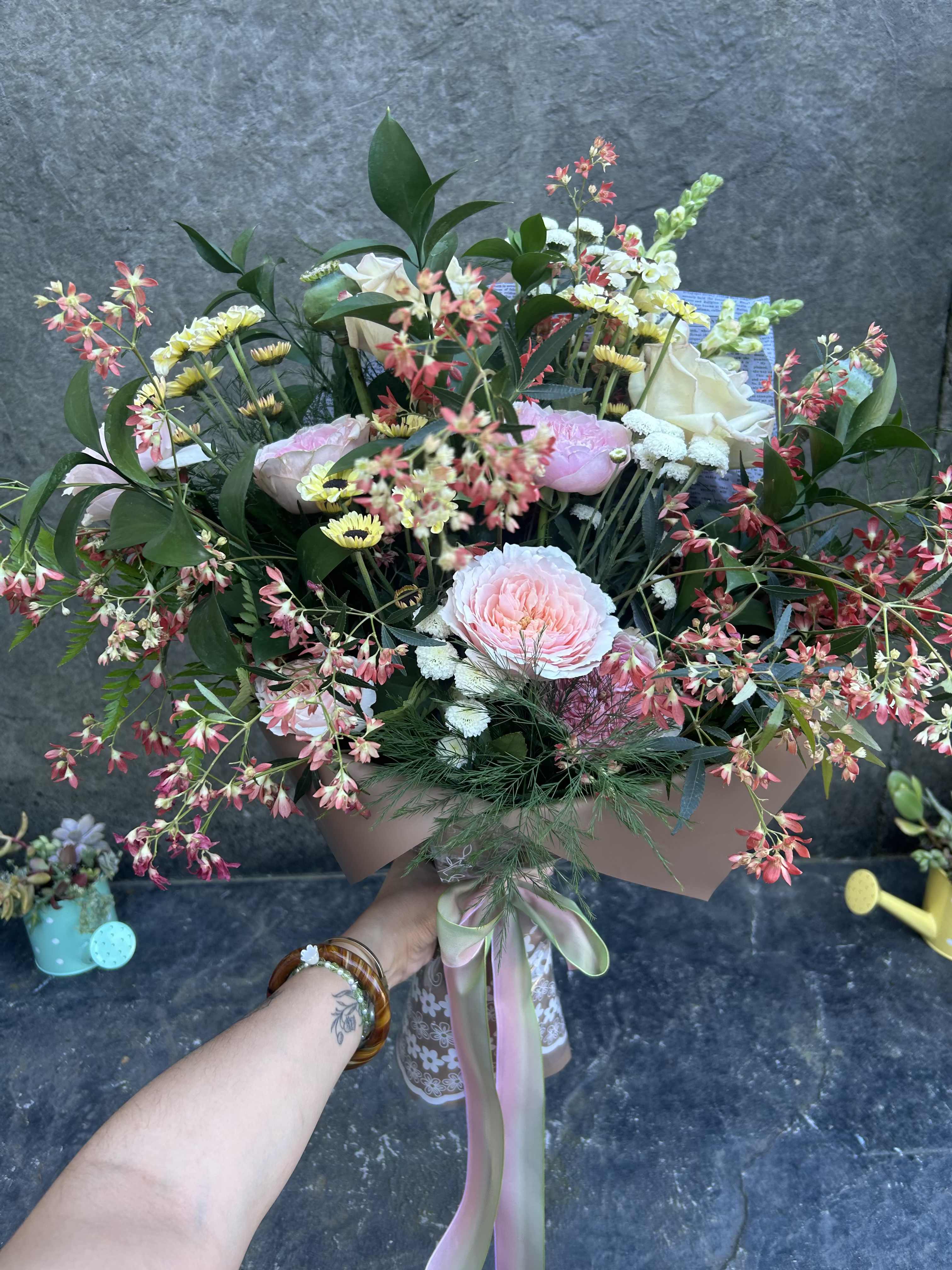 Garden Bliss - We don't always get Garden roses in but these lovelies just needed a home. Garden roses in pink,  lite pink, blush, with button mums, mini sunflowers, lovely festival bush, ferns, poppy pods, snapdragons, and greenery. Wrapped and tied with a ribbon.   *Reasonable substitutions may be made due to floral availability. Will have similar look and feel. 