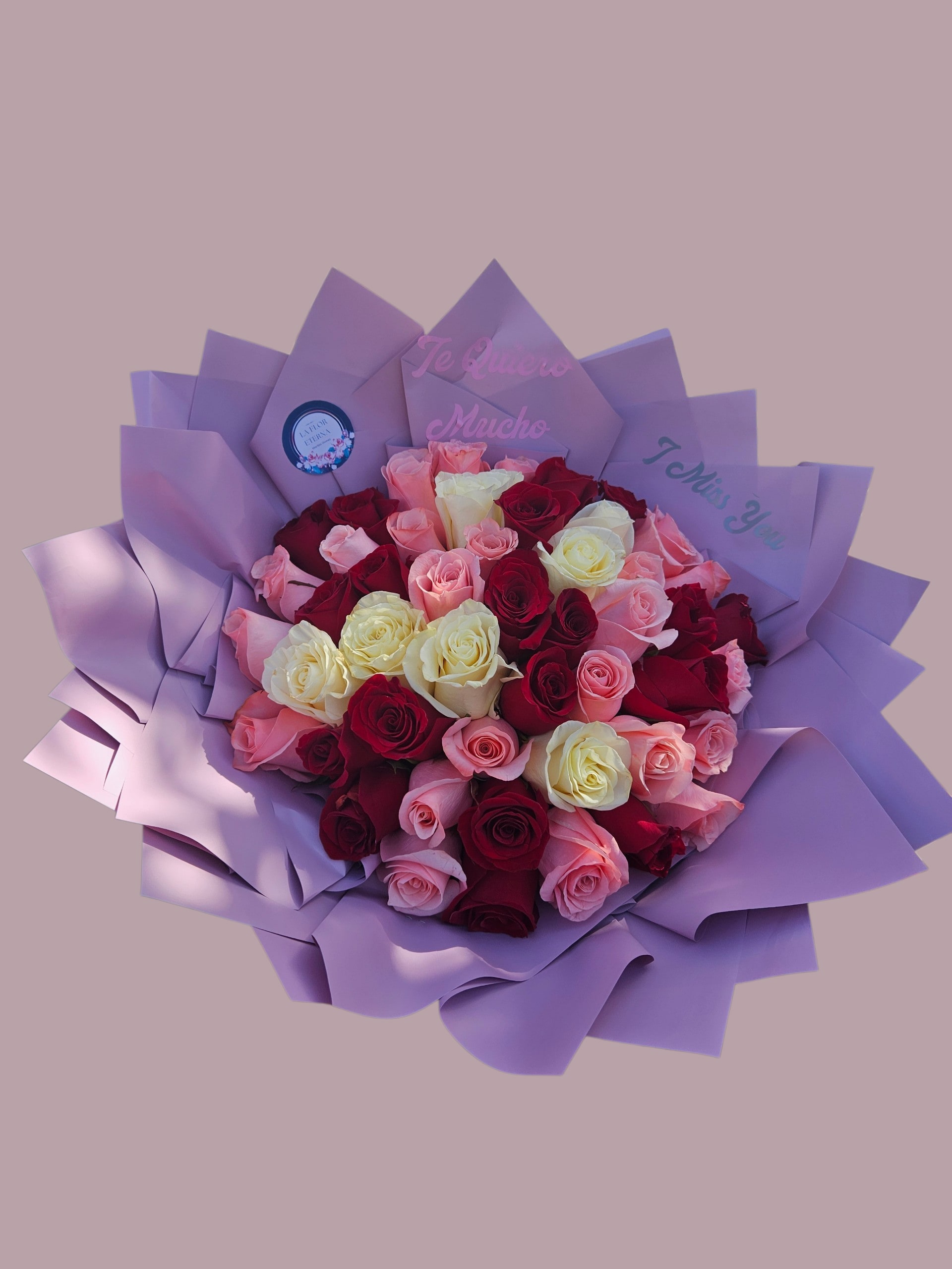 Suspiros de Pasión - A lush hand-tied bouquet of roses in deep red, blush pink, creamy white and a hint that reads as pure romantic drama - perfect as an anniversary roses gift, Valentine's Day bouquet, or a birthday arrangement to make someone feel adored. The dense, tightly clustered blooms create a bold visual statement while the layered lavender paper wrap softens the palette and adds a polished, gift-ready finish.  Choose this bouquet for moments when you want the recipient to feel truly seen and cherished - whether saying "I love you," celebrating a milestone, or sending a thoughtful thank-you. The lavender wrap helps protect stems in transit; order with standard sizing and same-day options when available to ensure peak freshness on arrival.