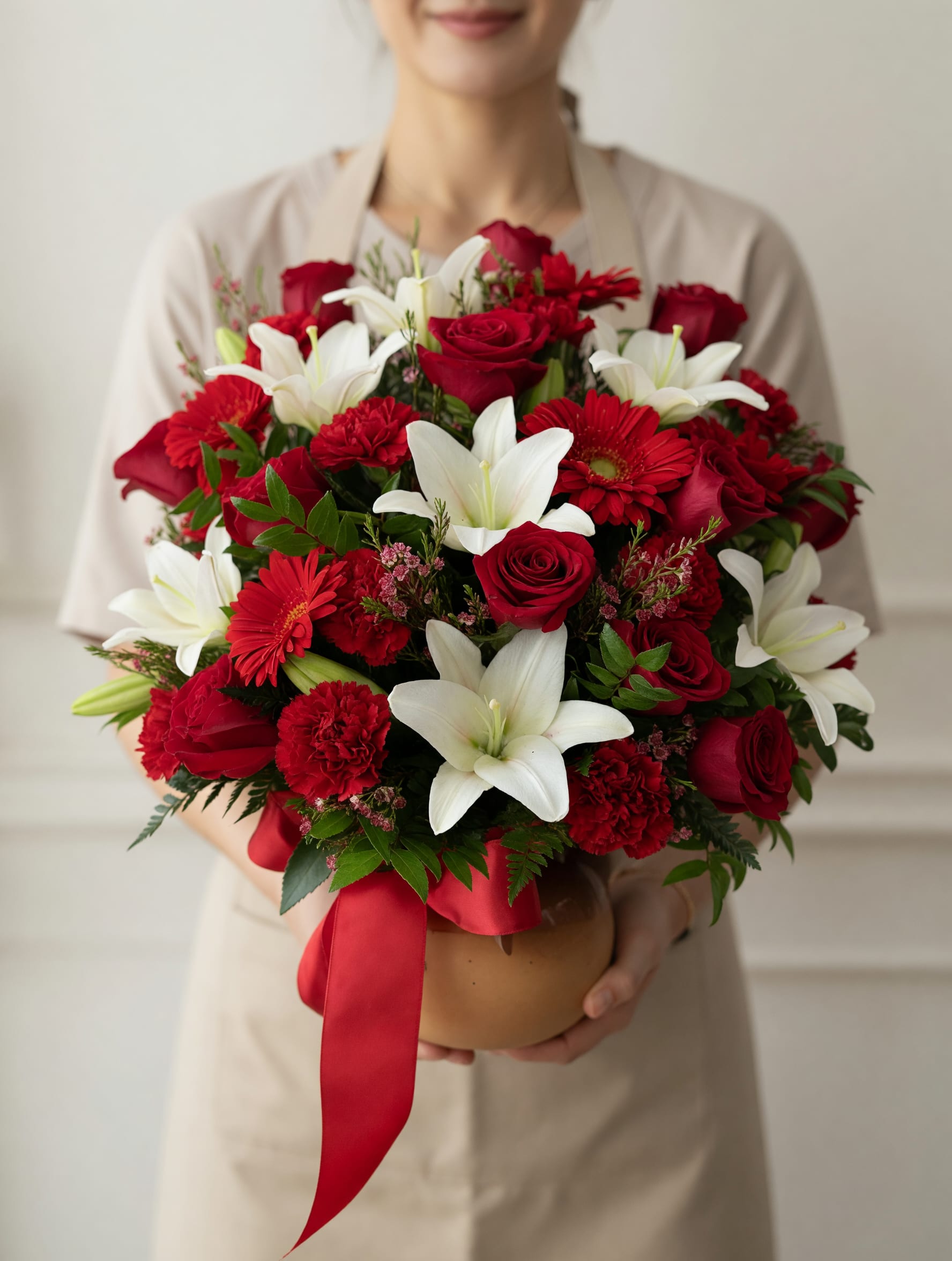 Para La Reina De Casa - Sorprende a mamá con un diseño floral lleno de pasión, elegancia y significado. Este hermoso arreglo combina la intensidad de las rosas rojas con la pureza de los lirios blancos y la delicadeza de flores complementarias, creando una composición sofisticada que transmite amor profundo y admiración. Presentado en una base elegante y adornado con un listón rojo, cada detalle ha sido cuidadosamente seleccionado para ofrecer una experiencia visual impactante y un regalo inolvidable. Su estilo clásico y refinado lo convierte en la opción perfecta para honrar a mamá en su día. Elaborado a mano por nuestros expertos floristas con flores frescas de la más alta calidad, este arreglo no solo decora, sino que emociona y deja huella en el corazón.    Porque mamá merece lo más hermoso… regálale flores que hablen por ti.