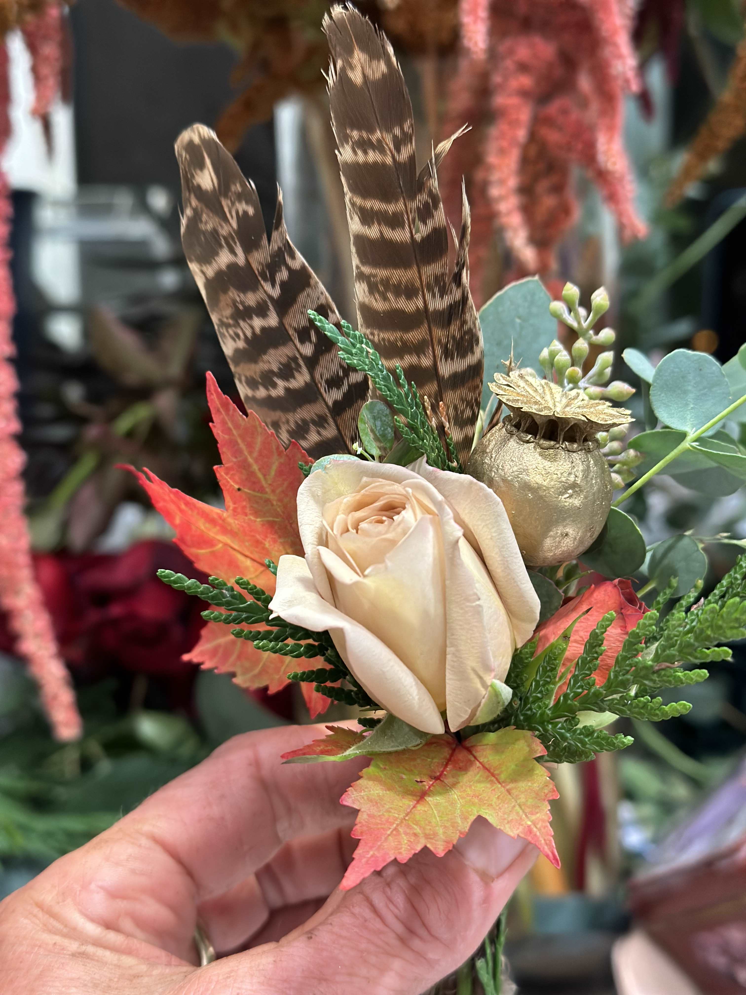 Cream rose with feathers, autumn leaves, and a gold pod accent