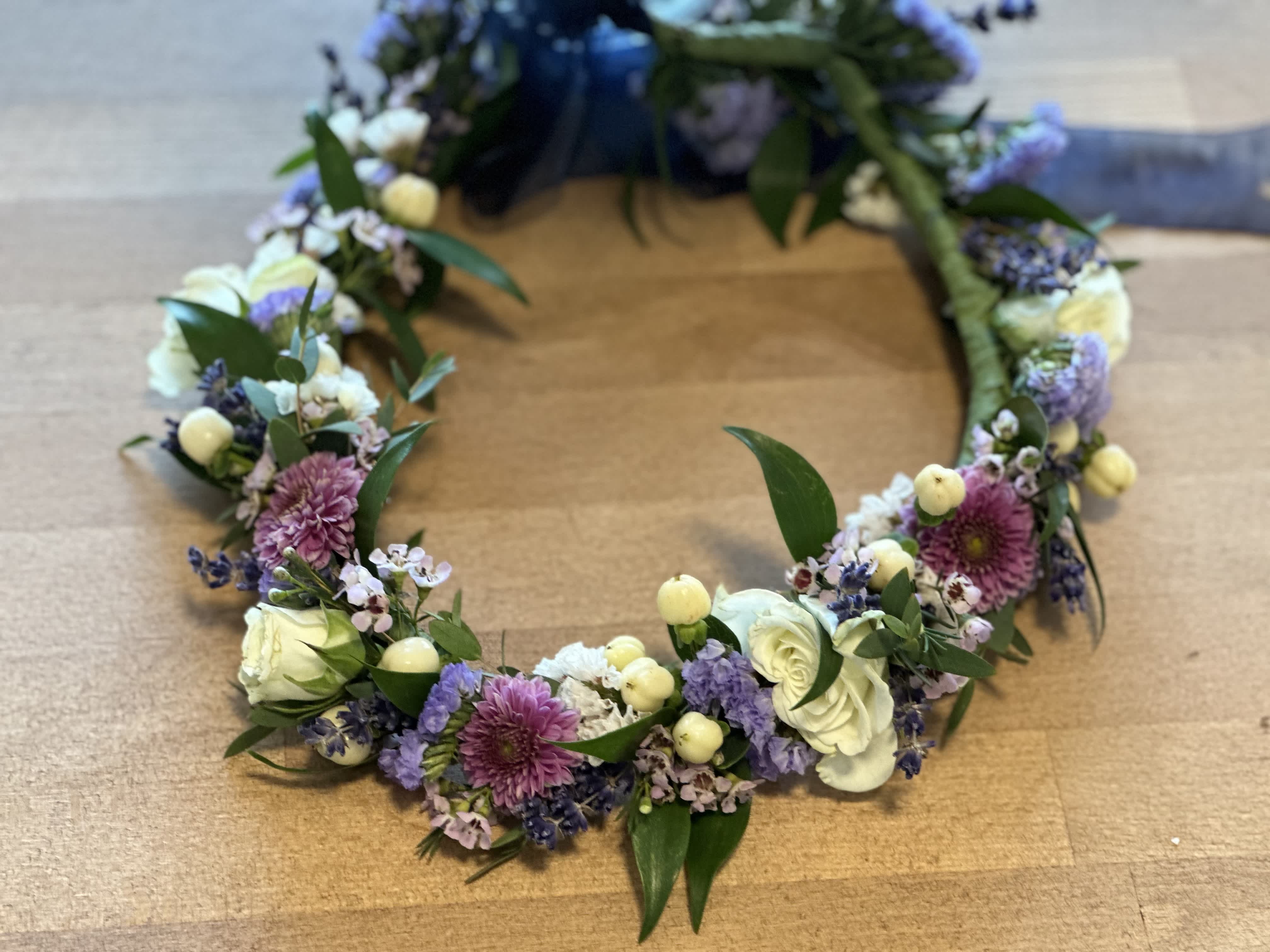 Floral wreath with white, purple, and pink blooms on a wooden surface