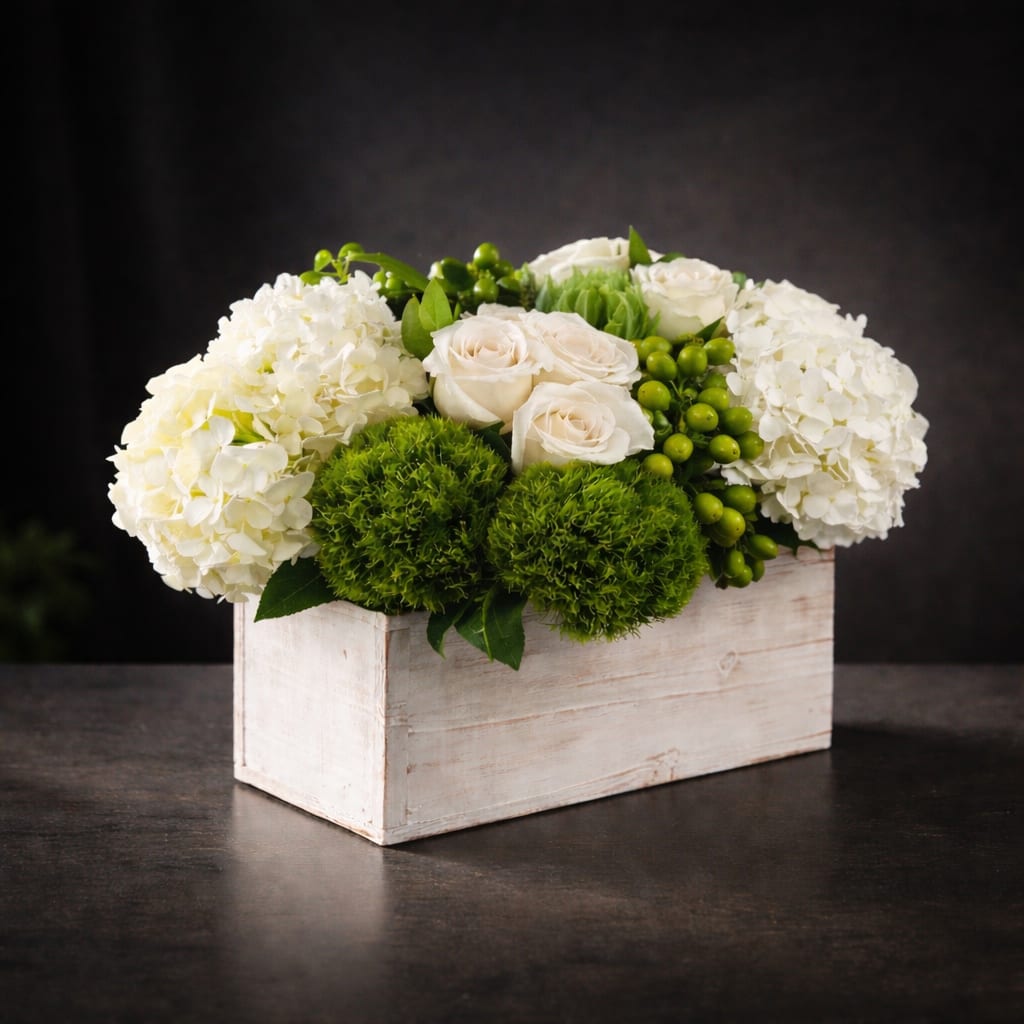 The Hamptons by BloomNation™ - This crisp white and green arrangement includes roses, dianthus, and hydrangeas. The Hamptons by BloomNation™ is the perfect gift for a Grandparents Day, Earth Day, or just because. It's size and shape also make it a fitting centerpiece for any table.   APPROXIMATE DIMENSIONS 18" W X 10" H