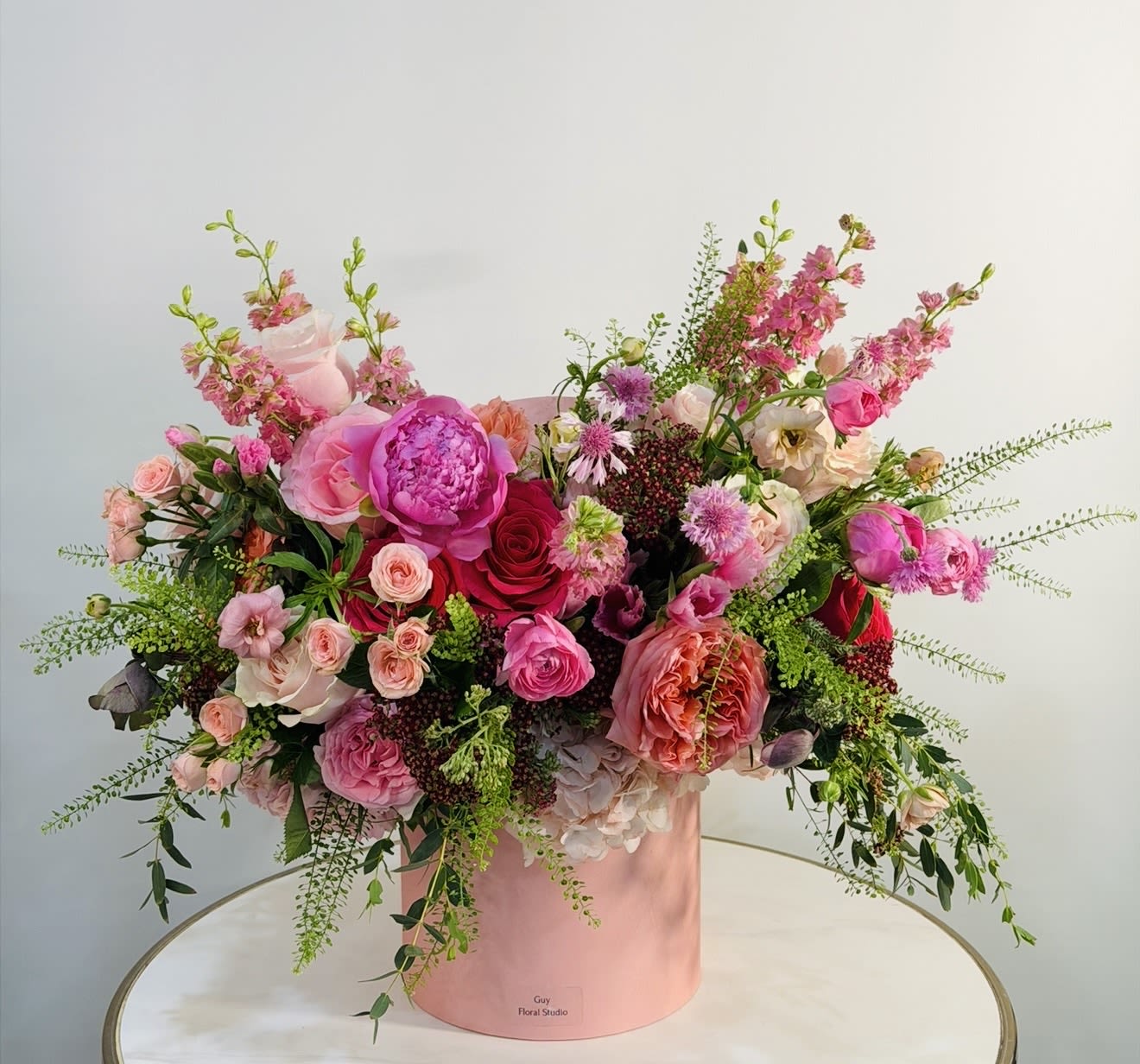Blush Peony Garden Arrangement - A luxurious and romantic floral arrangement designed by Guy Floral Studio, featuring an exquisite blend of premium blooms in soft blush, pink, and vibrant red tones. This elegant composition includes lush peonies, garden roses, spray roses, ranunculus, and seasonal accent flowers, all beautifully arranged in a modern velvet-style hat box. The peonies bring a rich, full texture and a sense of timeless luxury, making this arrangement perfect for birthdays, anniversaries, romantic gestures, or upscale home décor. The organic, garden inspired design creates a natural yet sophisticated look that stands out in any space. We proudly offer same day flower delivery across: Beverly Hills, Bel Air, West Hollywood, Hollywood Hills, Beverly Grove, Culver City, and Santa Monica. Each arrangement is handcrafted with care to ensure freshness, beauty, and a premium floral experience.