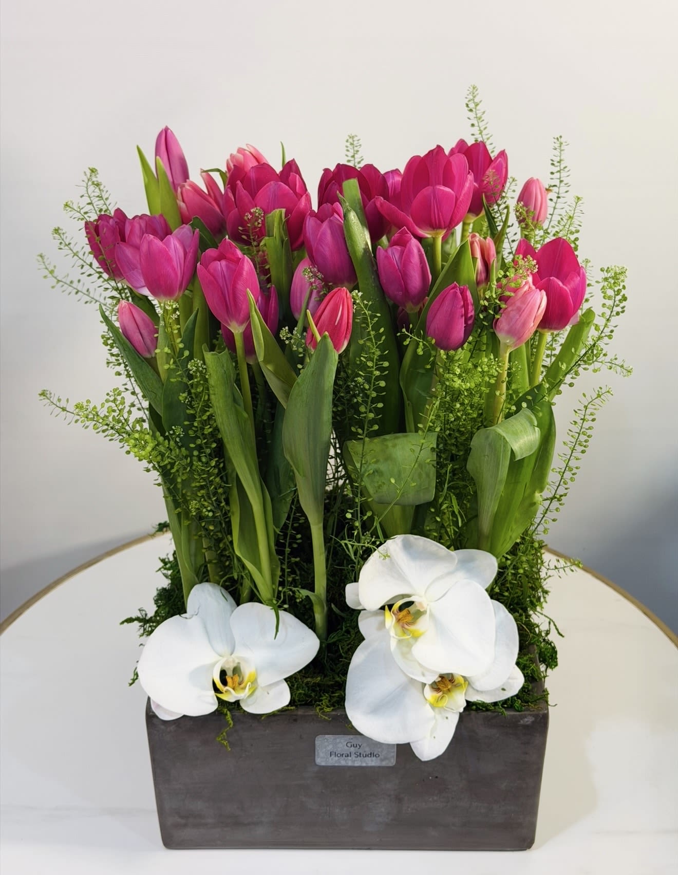 Elegant Tulip &amp; Orchid Garden  - A sophisticated and modern floral arrangement by Guy Floral Studio, featuring vibrant pink tulips paired with elegant white orchids. This fresh and refined design is arranged in a sleek rectangular container, complemented by lush greenery for a natural garden inspired look. The bold pink tulips symbolize love, happiness, and renewal, while the white orchids add a touch of luxury and elegance. Together, they create a striking contrast that feels both contemporary and timeless perfect for birthdays, thank you gifts, celebrations, or upscale home styling. This arrangement is ideal for anyone who appreciates clean, modern floral design with a luxurious twist. We offer same day flower delivery throughout: Beverly Hills, Bel Air, West Hollywood, Hollywood Hills, Beverly Grove, Culver City, and Santa Monica. Each piece is handcrafted with premium flowers to ensure freshness, beauty, and a high-end floral experience.