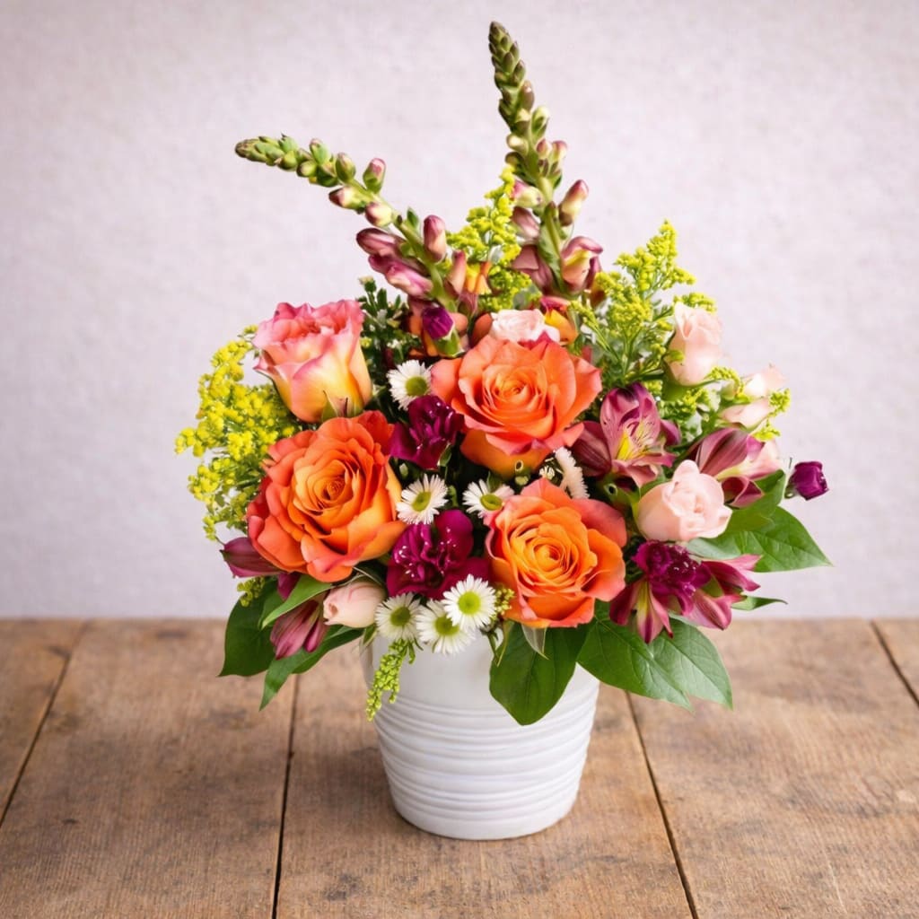 Blooming Blossoms  - Enhance your home decor with our stunning vase filled with a vibrant mix of orange and pink roses. Perfect for adding a pop of color and elegance to any room, these fresh flowers will brighten up your space and create a warm and inviting atmosphere. Ideal for special occasions or as a thoughtful gift for a loved one, this beautiful arrangement is sure to impress.   A unique arrangement of orange roses, snapdragons, and beautiful filler flowers to brighten your special someone's day. Hand-created by our experienced designers. Please note that every design is custom made and substitution to container and flower types may happen from time to time. Design aspects will always stay the same, but if needed, we will substitute with flowers of equal or greater value to offer you a great floral shopping experience! Our flowers are 100% guaranteed. Please call us with any questions or concerns.