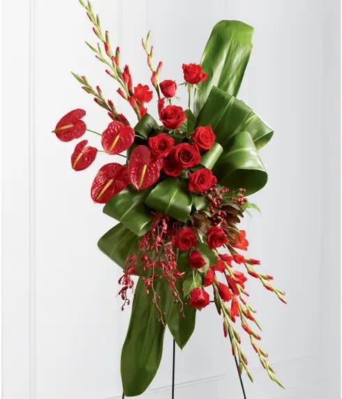 Red roses with anthuriums and tropical foliage on a stand