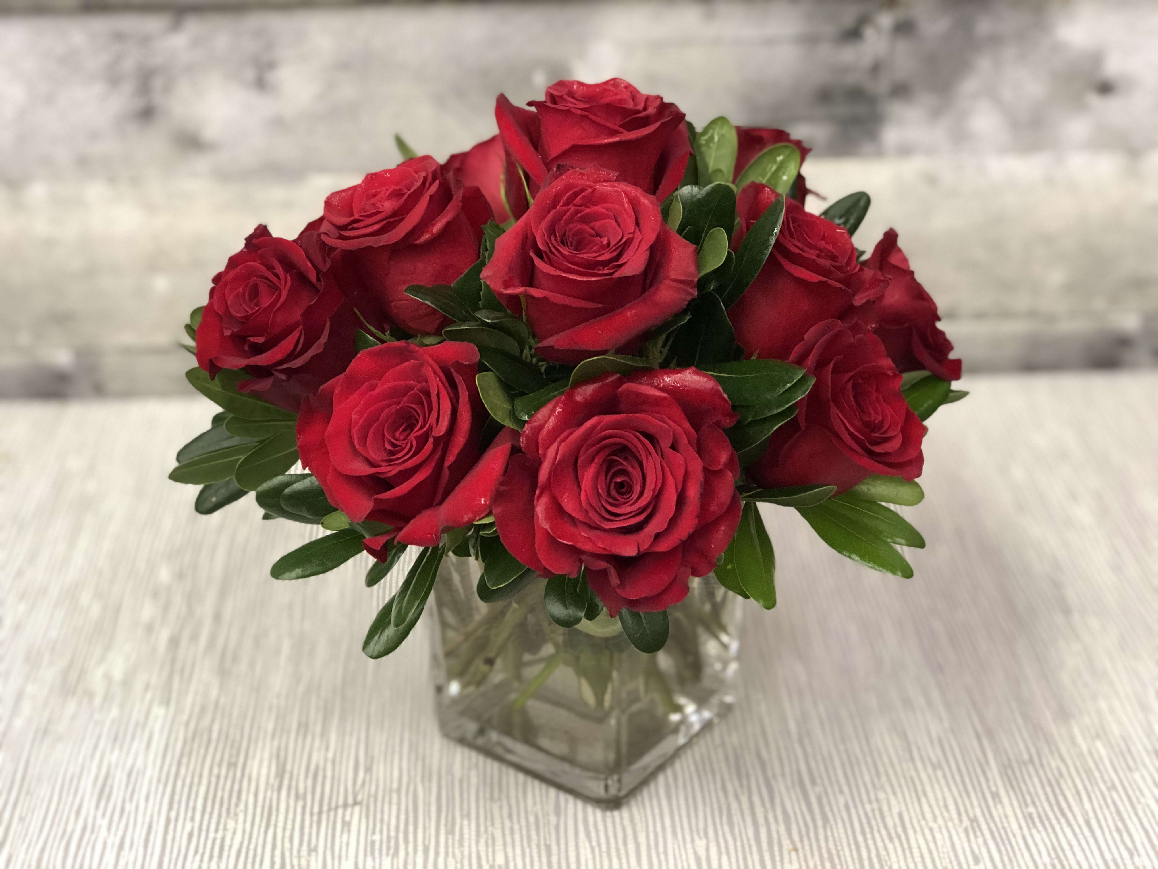 Red roses arranged in a clear glass vase