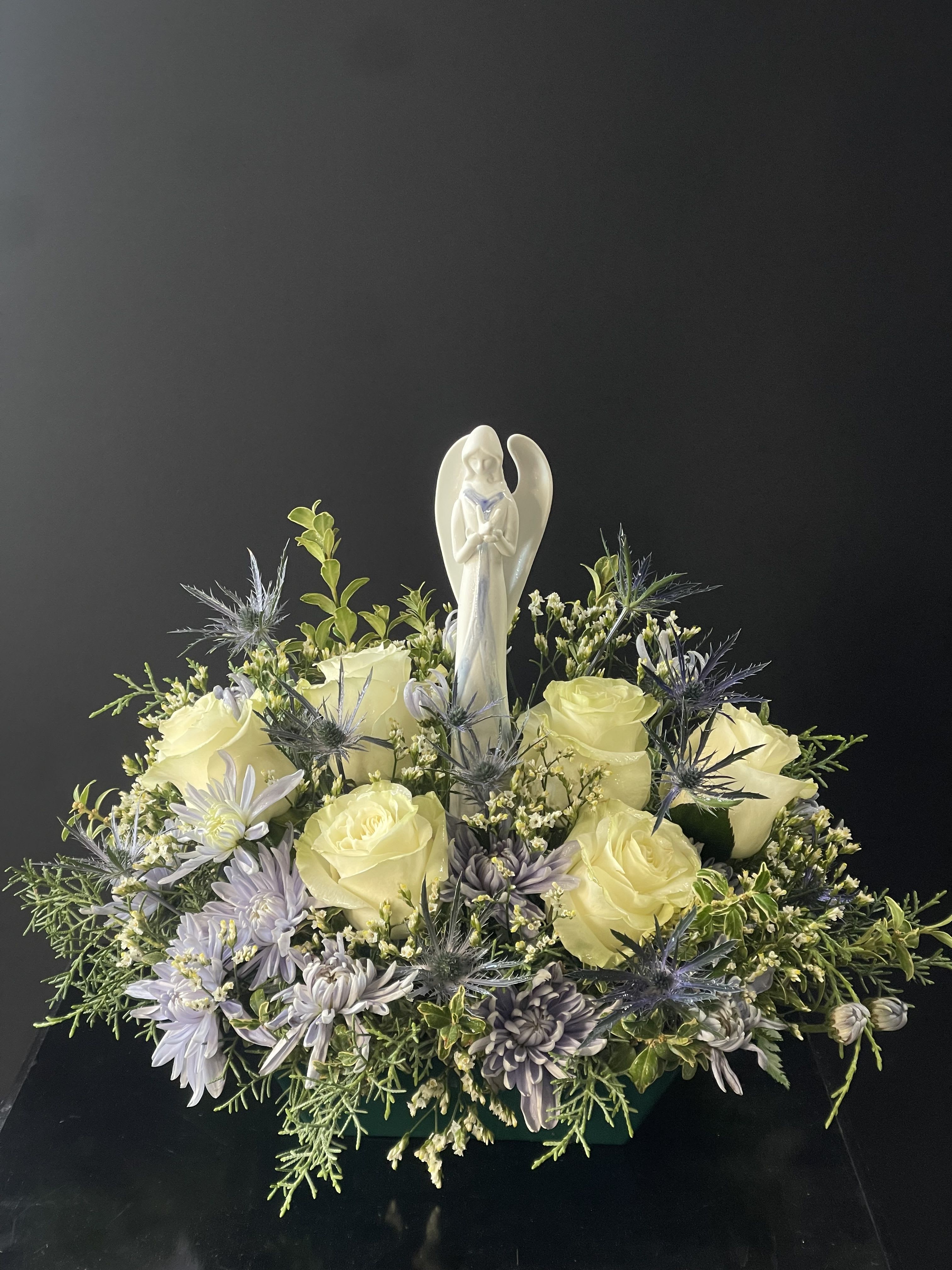 Cream roses and lavender flowers arranged around an angel figurine