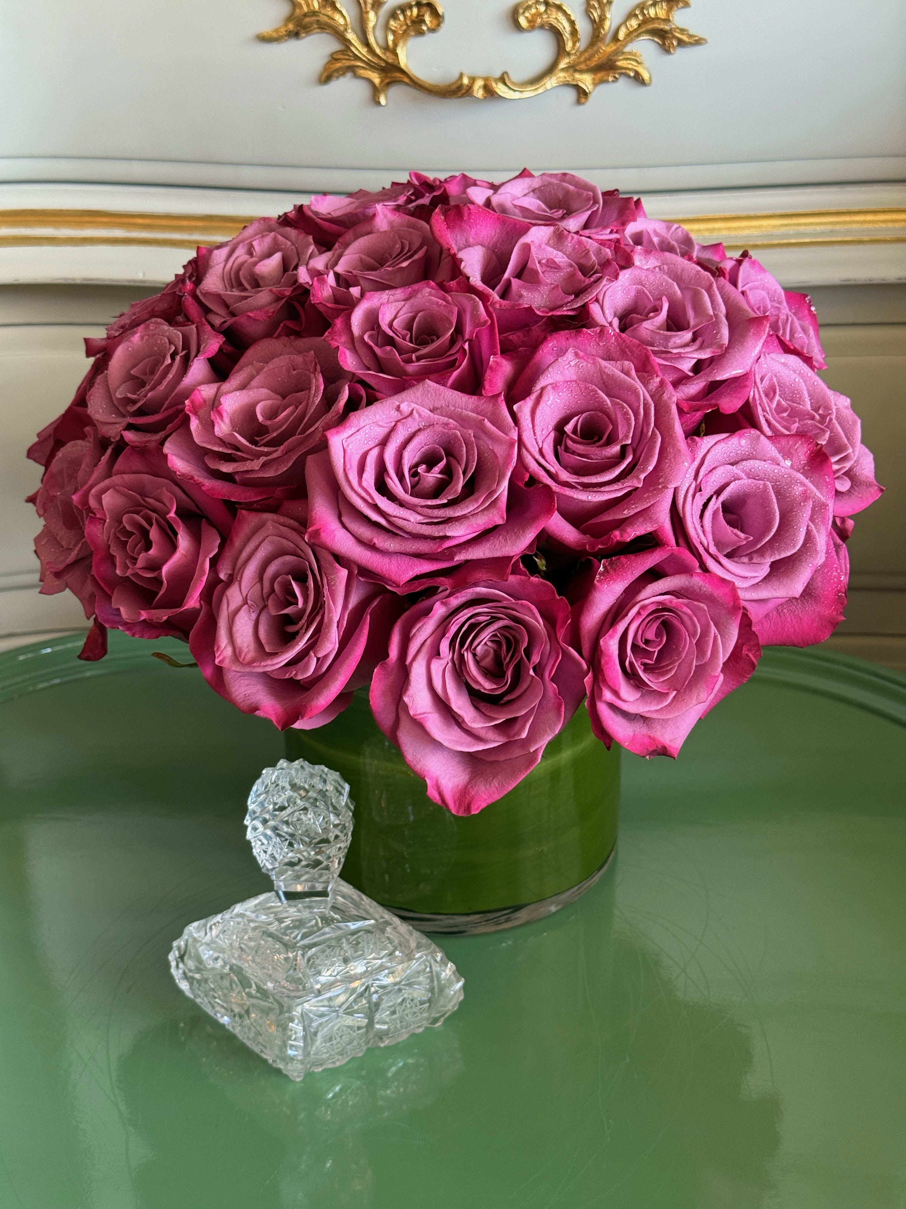Pink rose bouquet in a green glass vase with a crystal figurine in front