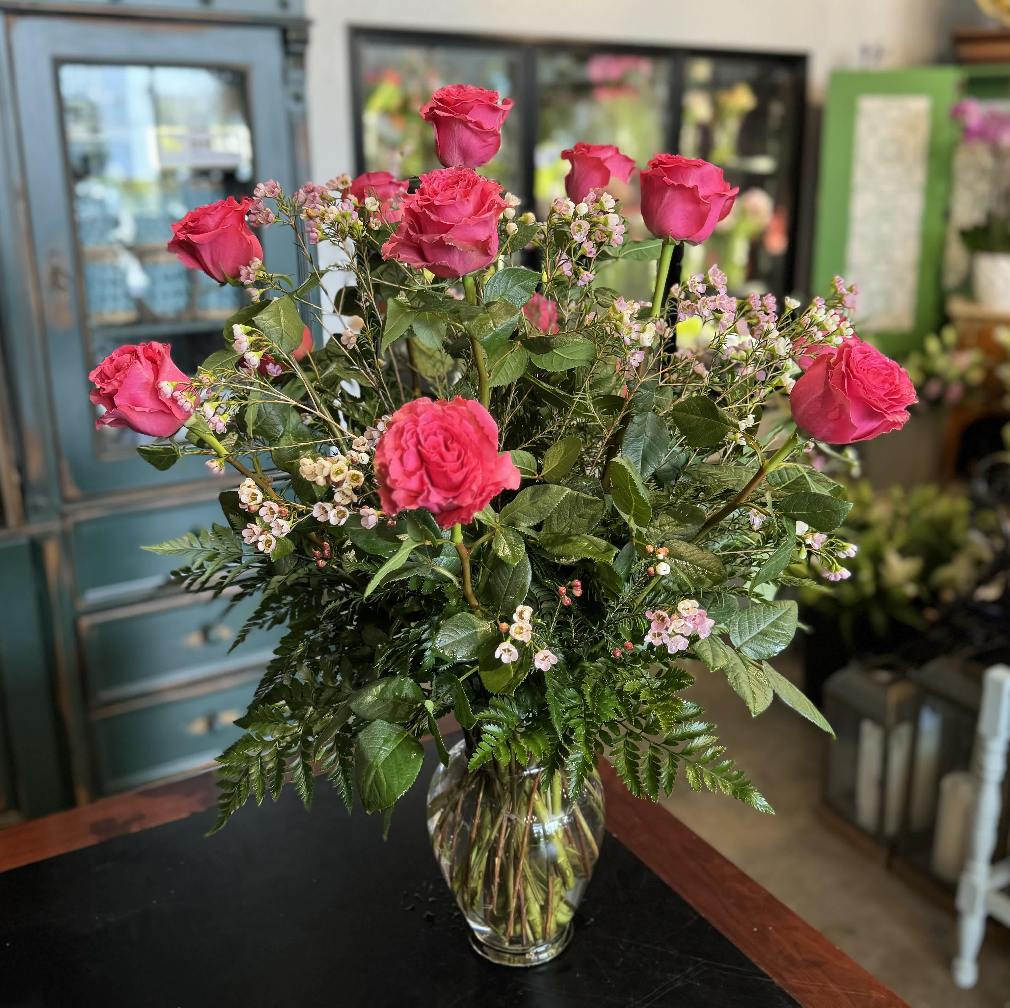 Pink roses arranged in a clear glass vase with small filler flowers