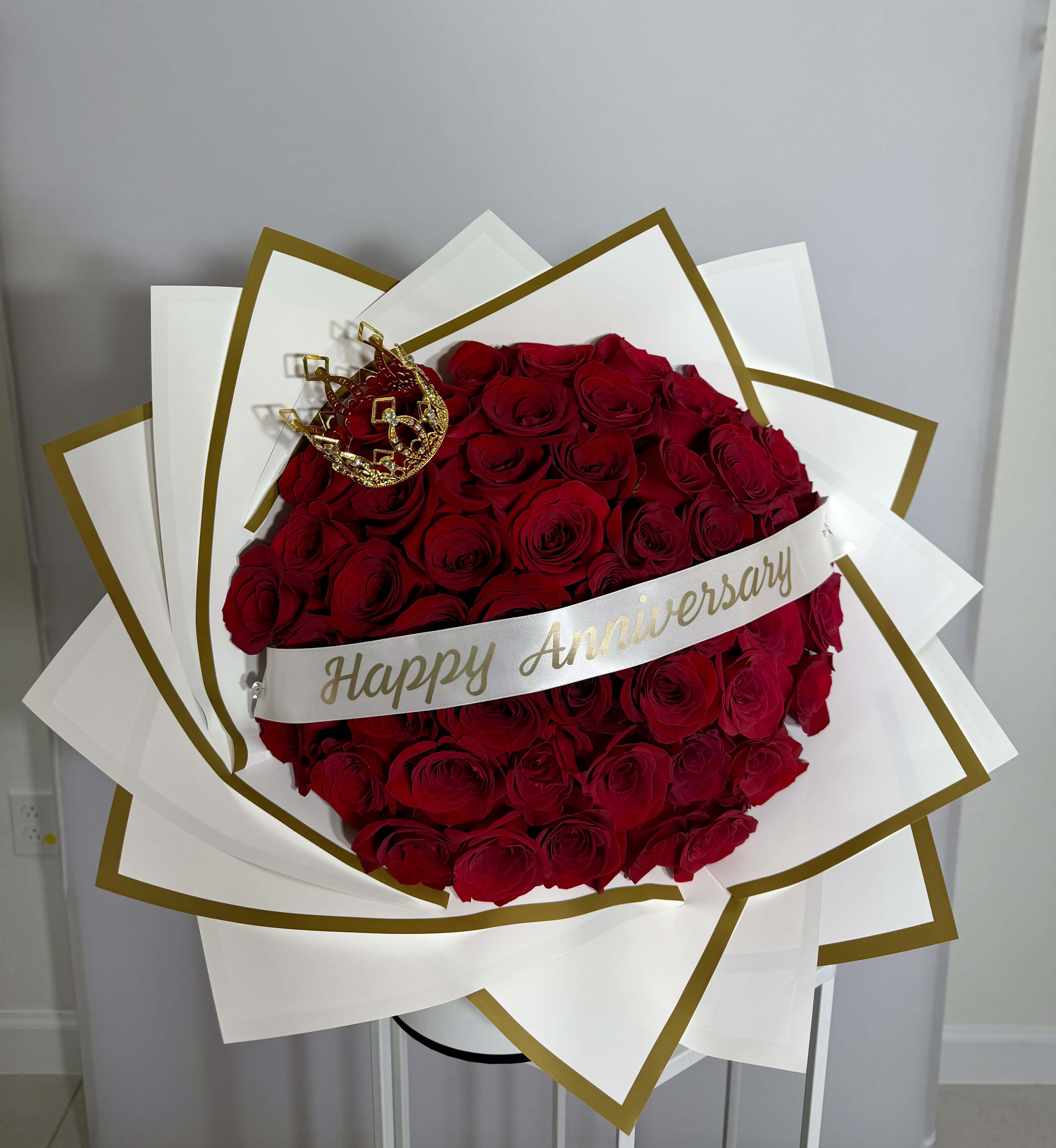 Anniversary Queen Bouquet - Classic red roses wrapped in white paper with elegant gold details, finished with a crown. Made with fresh natural flowers, the perfect way to celebrate love and anniversaries. 
