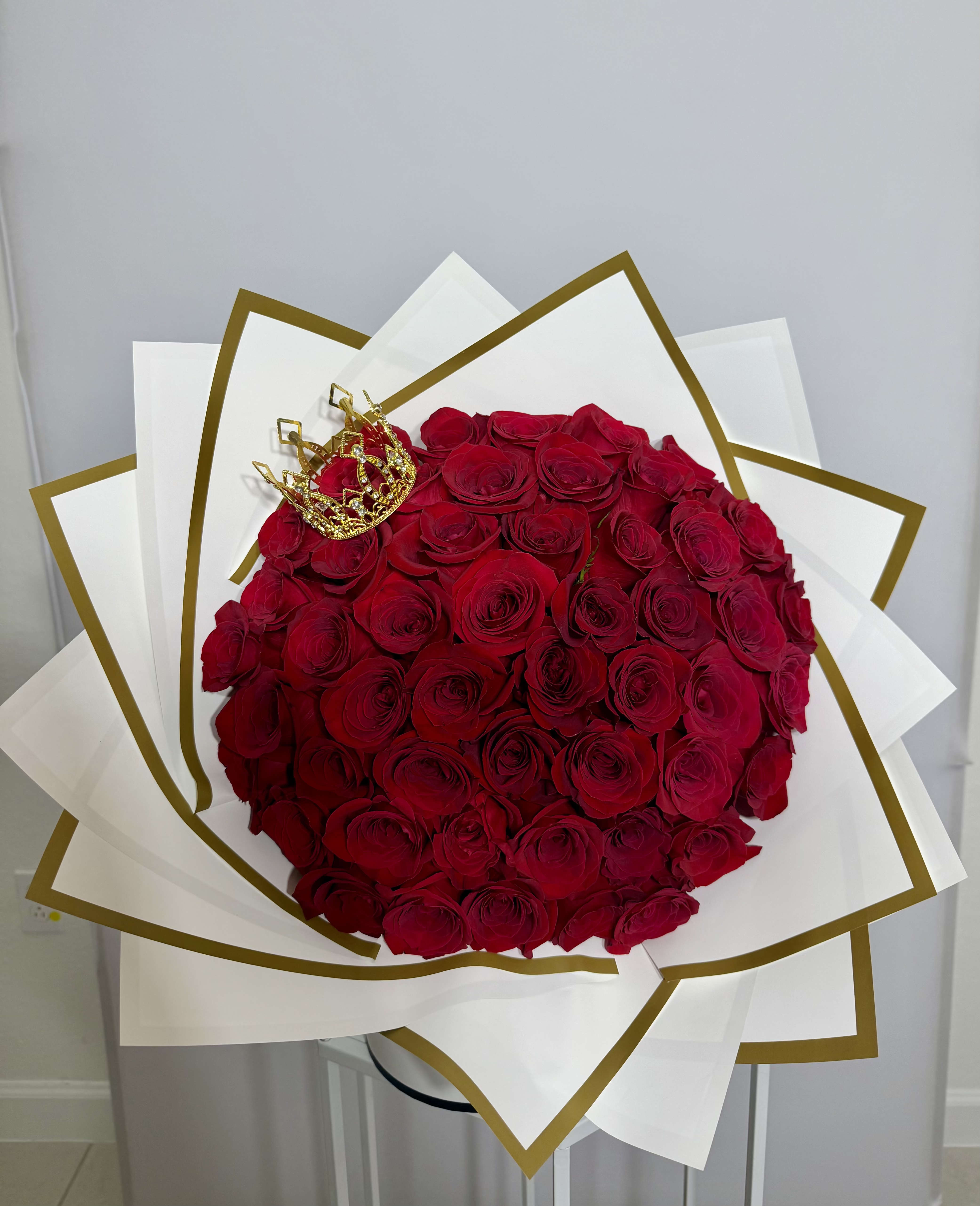 Queen Bouquet - Classic red roses wrapped in white paper with elegant gold details, finished with a crown made for royalty. Made with fresh natural flowers. 