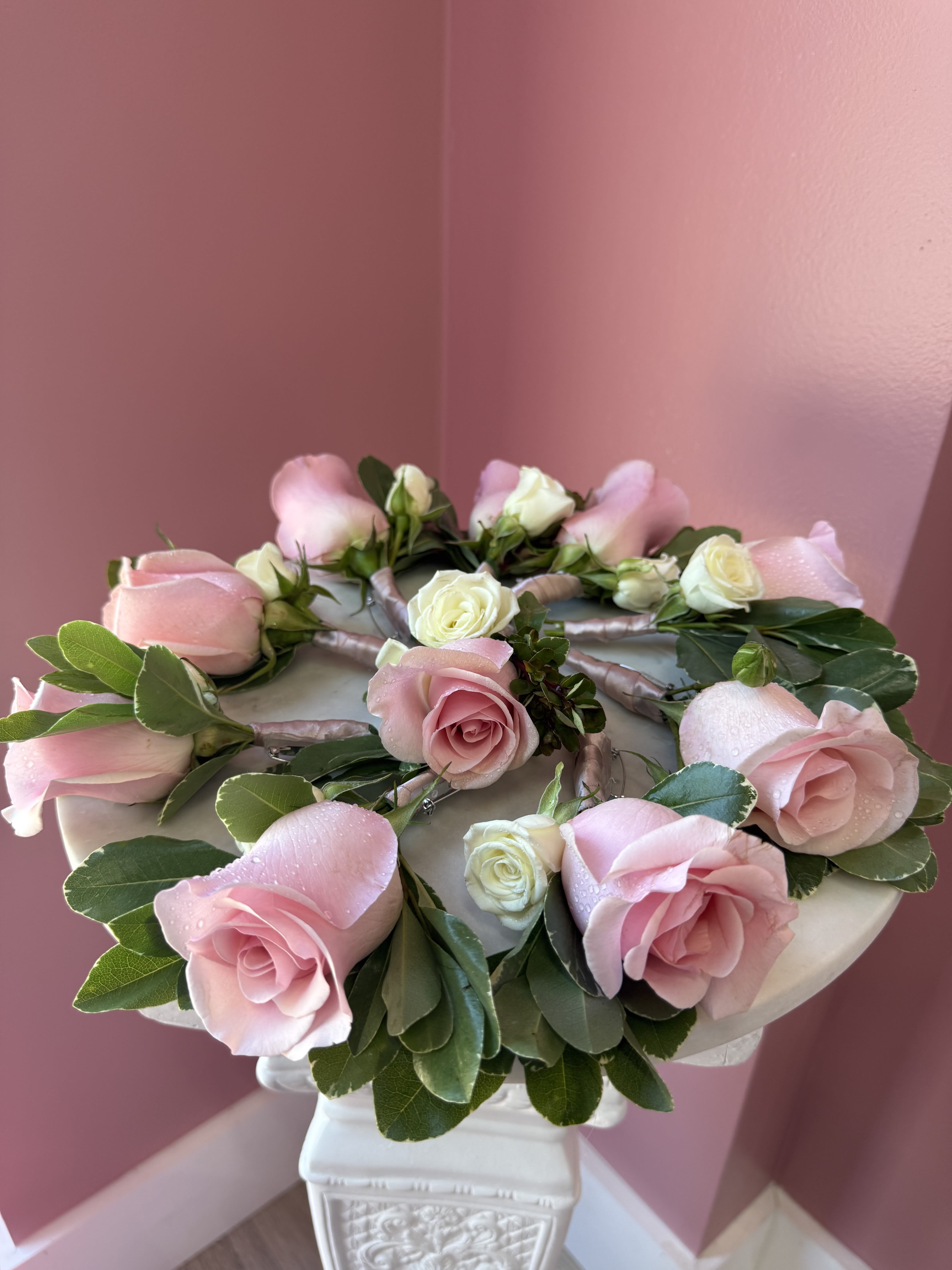 Wedding Boutonnière  - Typically worn on a lapel, it consists of a single rose bud. It is accented with deep green leaves (often Israeli Ruscus or Eucalyptus) and secured with a pin